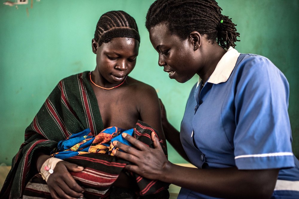  Munges Veronica, 24, holds her newborn baby, Teko, with Atim Jane, a 38 year old nursing officer at the Nadunget Health Center 3 in Karamoja, Uganda. 