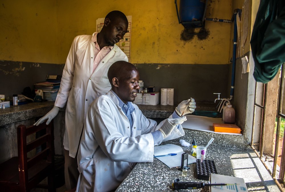  Mwiru Ali, a lab assistant, inspects a blood sample at the Busowobi health center in Iganga District, Uganda. 