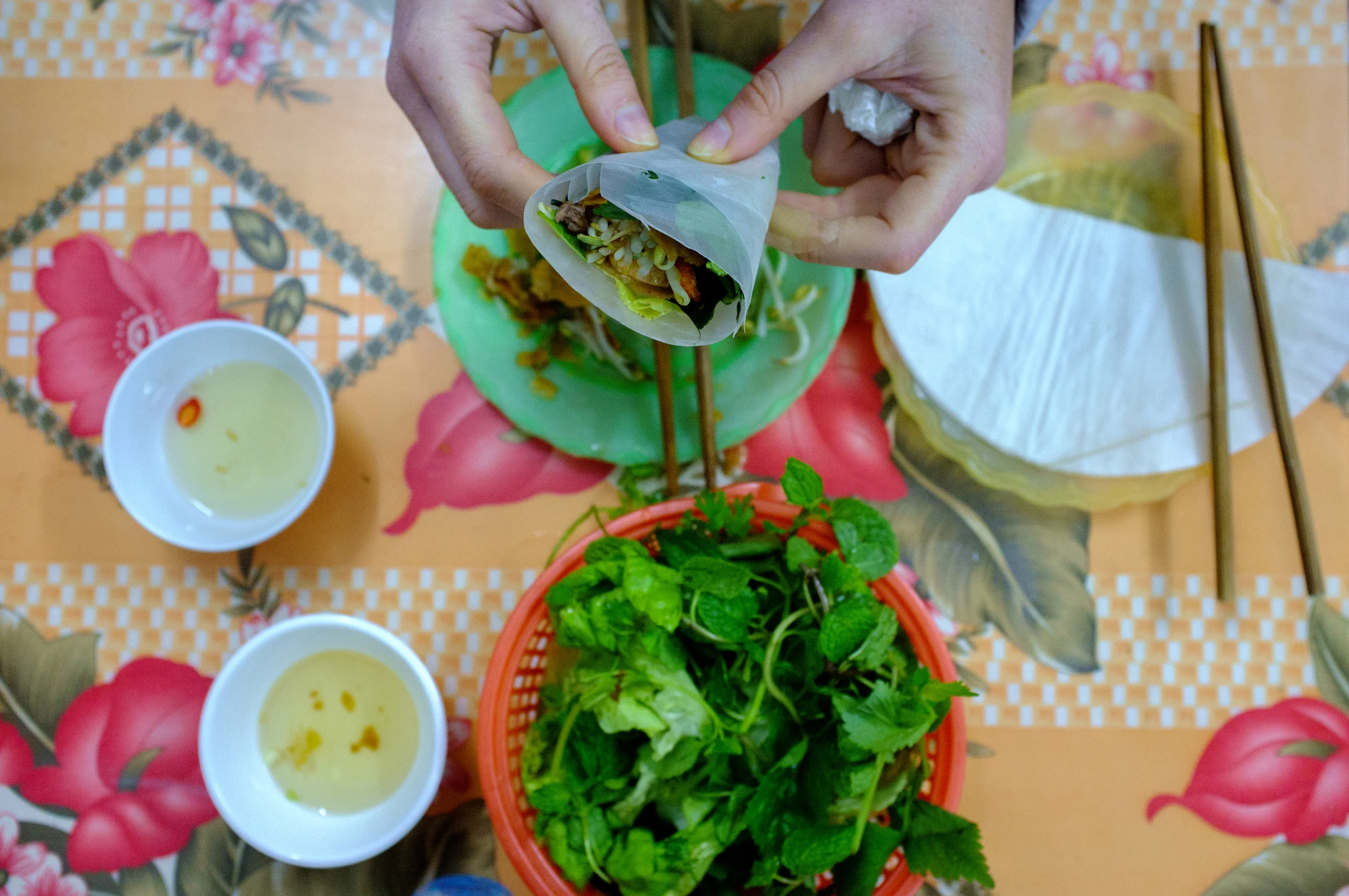 In Hanoi, bánh xèo is eaten wrapped with herbs in bánh tráng (rice paper)