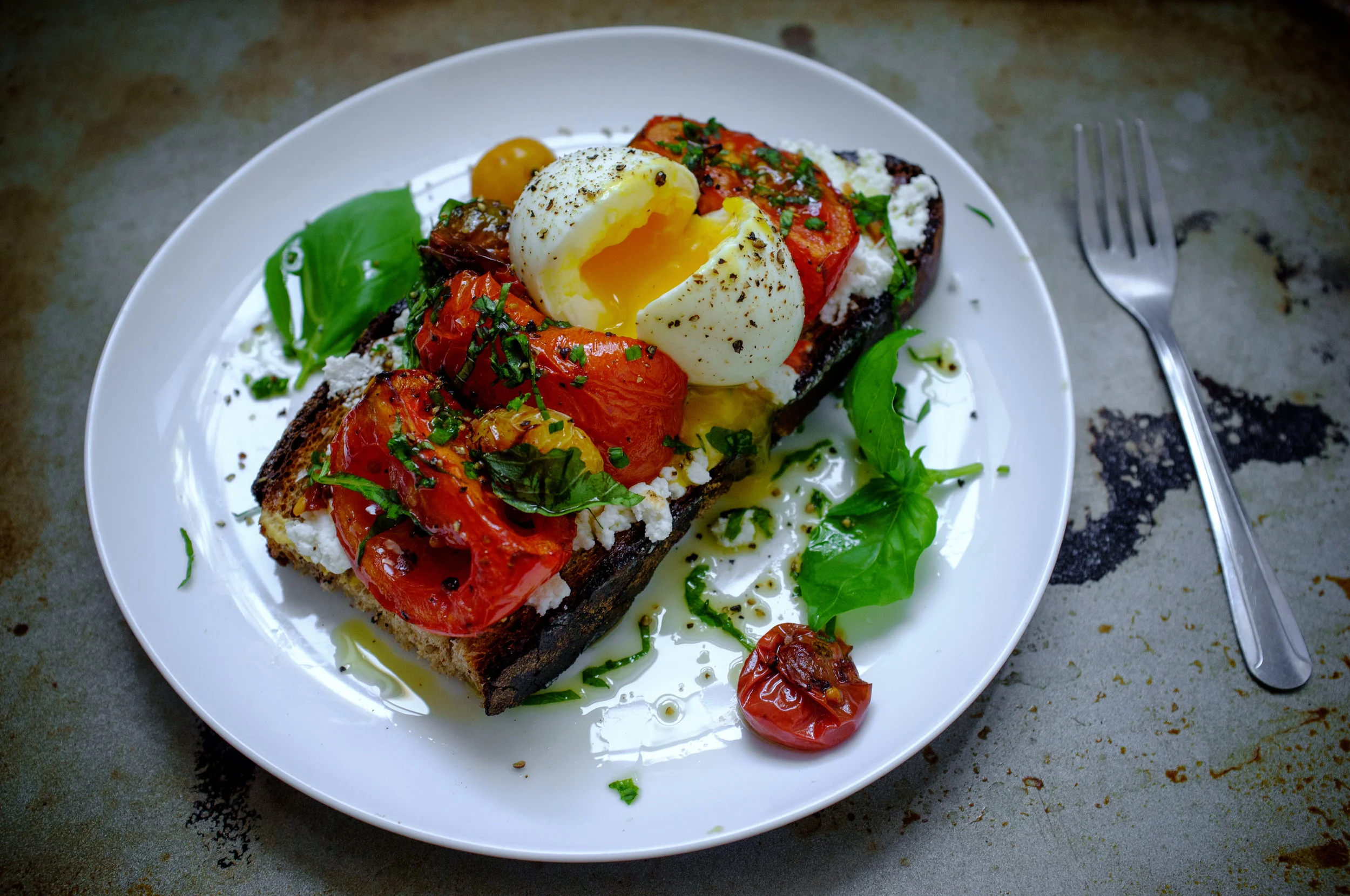 Roasted tomato tartine topped with a soft boiled egg and basil