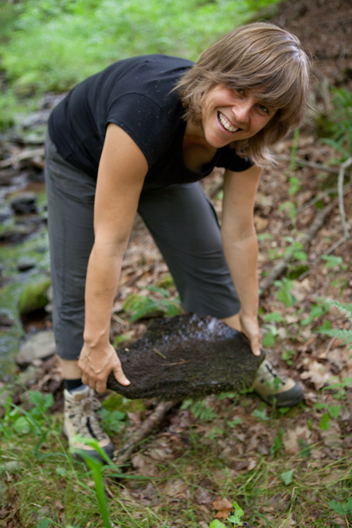 Isabelle collects rocks from the river to create a drainage system around the structure.