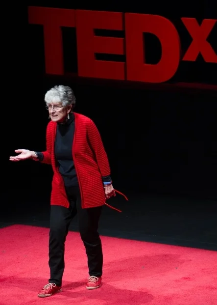 Monique Sternin presenting at TEDxMidAtlantic, October 2013, with red glasses in hand. 
