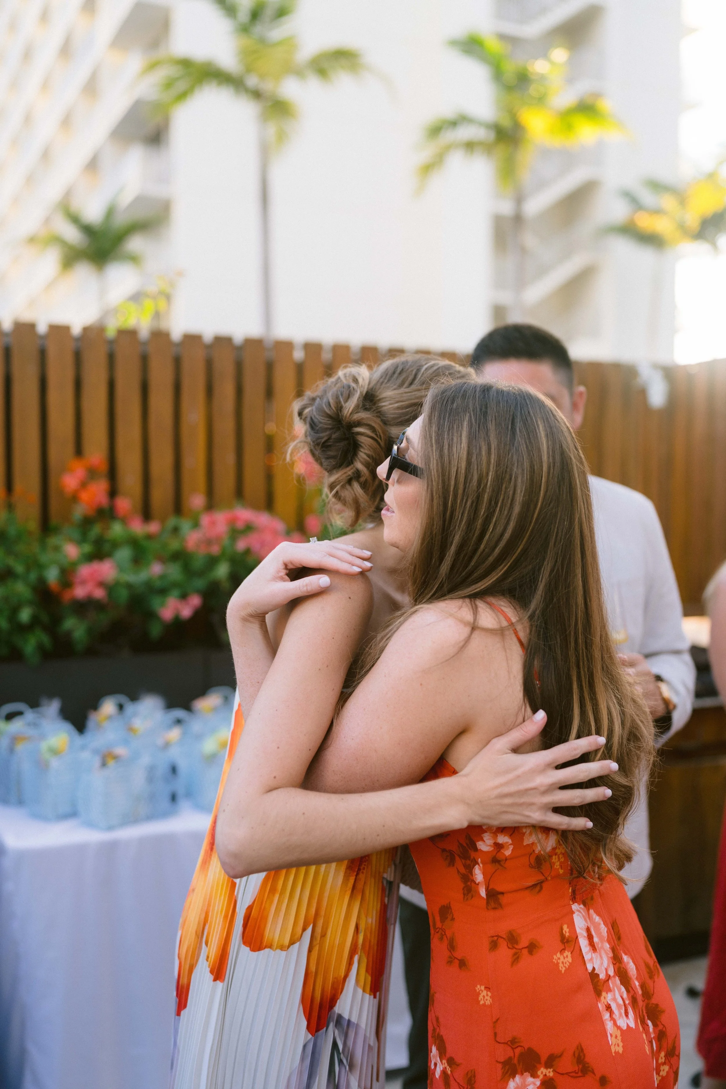 bride and friend embrace in hug at wedding welcome party