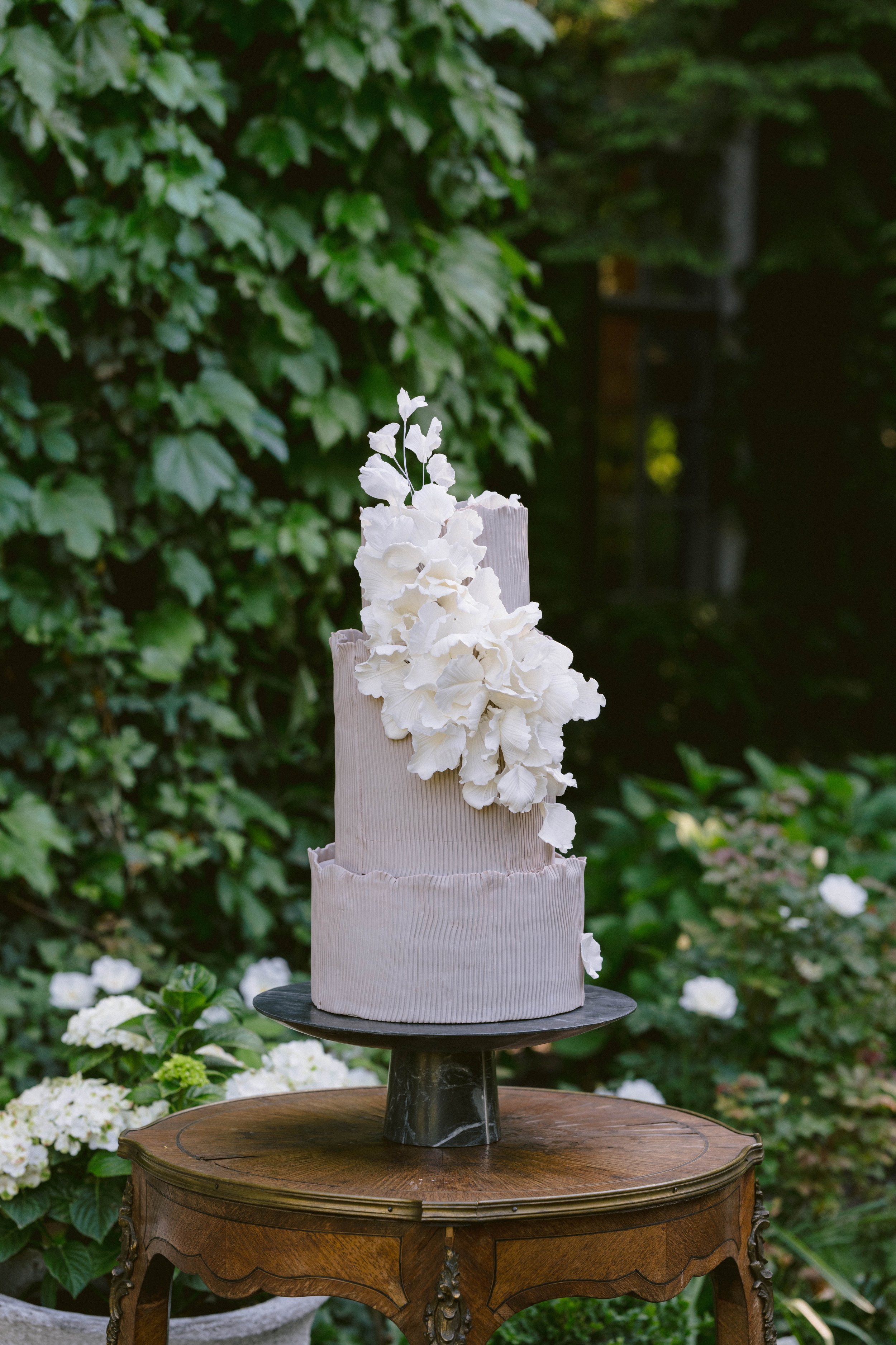 Cantigny gardens wedding cake on an antique table with black marble cake stand