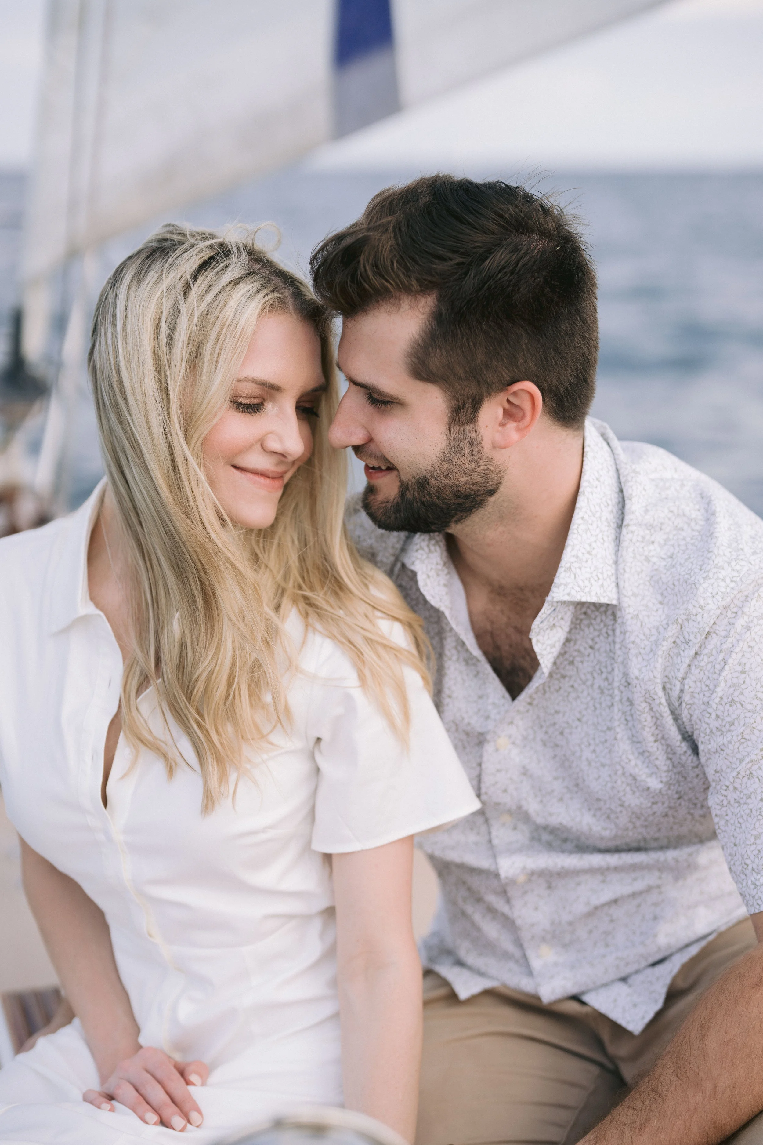 bride and groom seated on a sailboat with their heads close sharing a romantic moment while sailing lake michigan near chicago