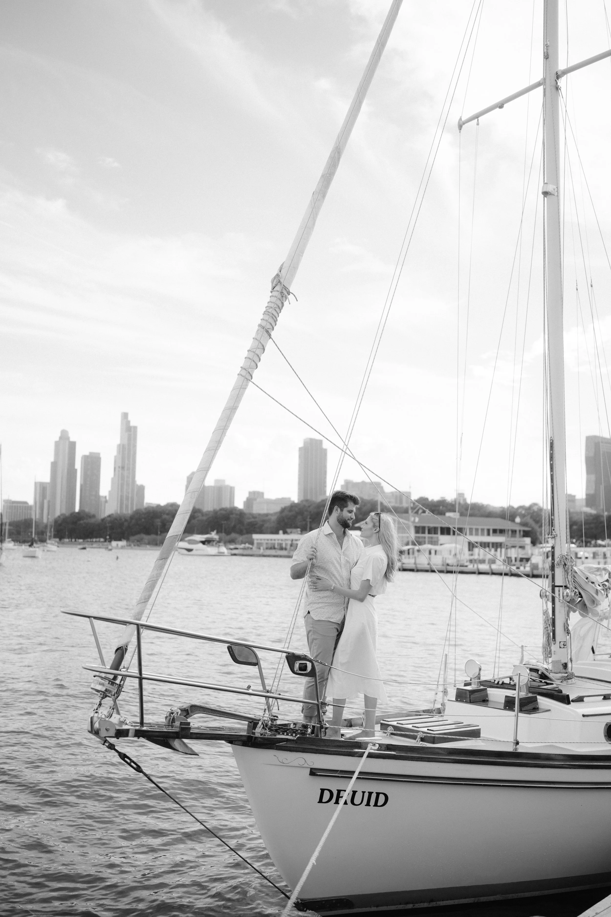couple standing on a sailboat that is docked at the marina in Chicago for engagement photos