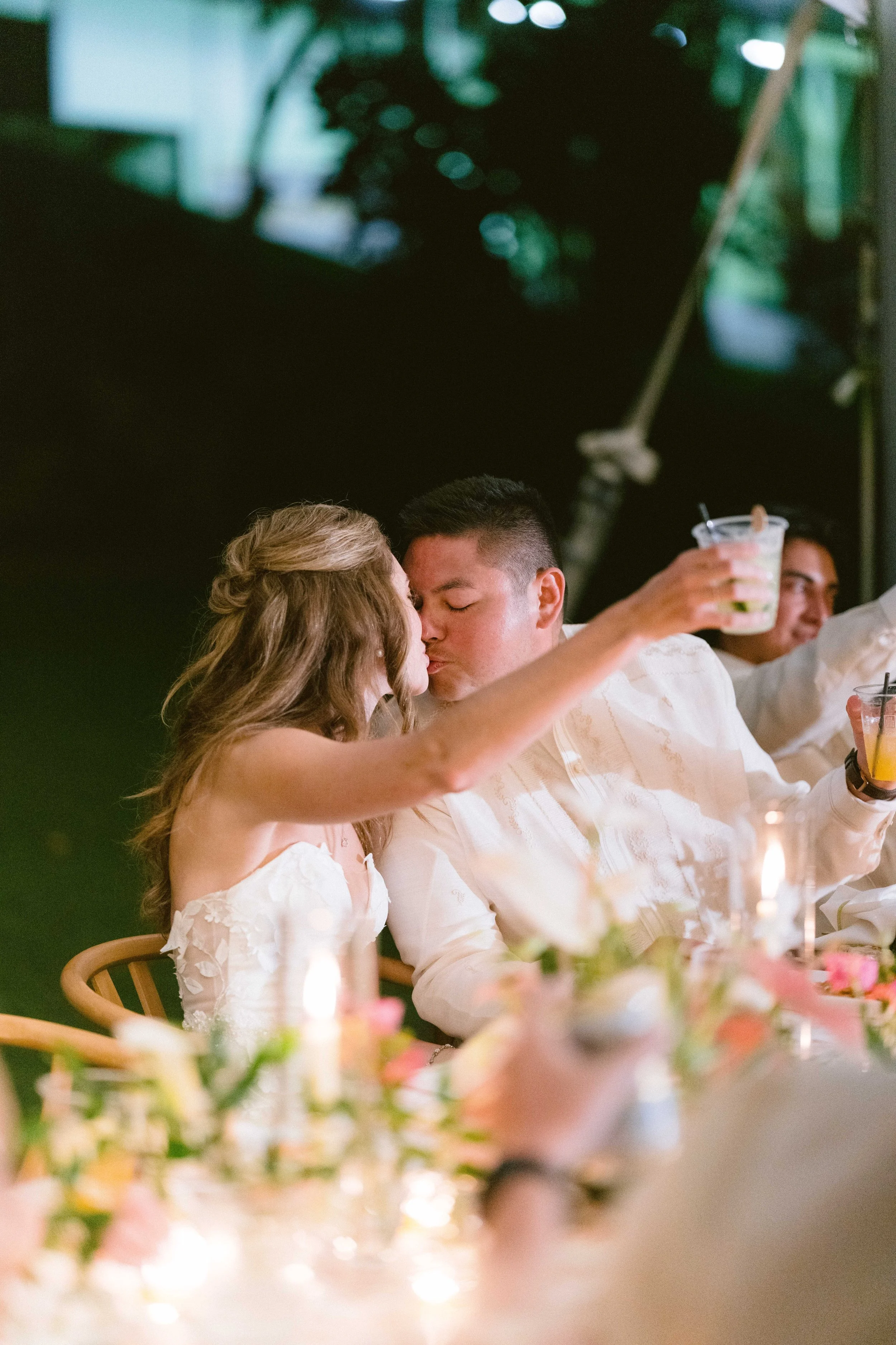 bride and groom toast and kiss after a speech at their wedding reception at kualoa ranch