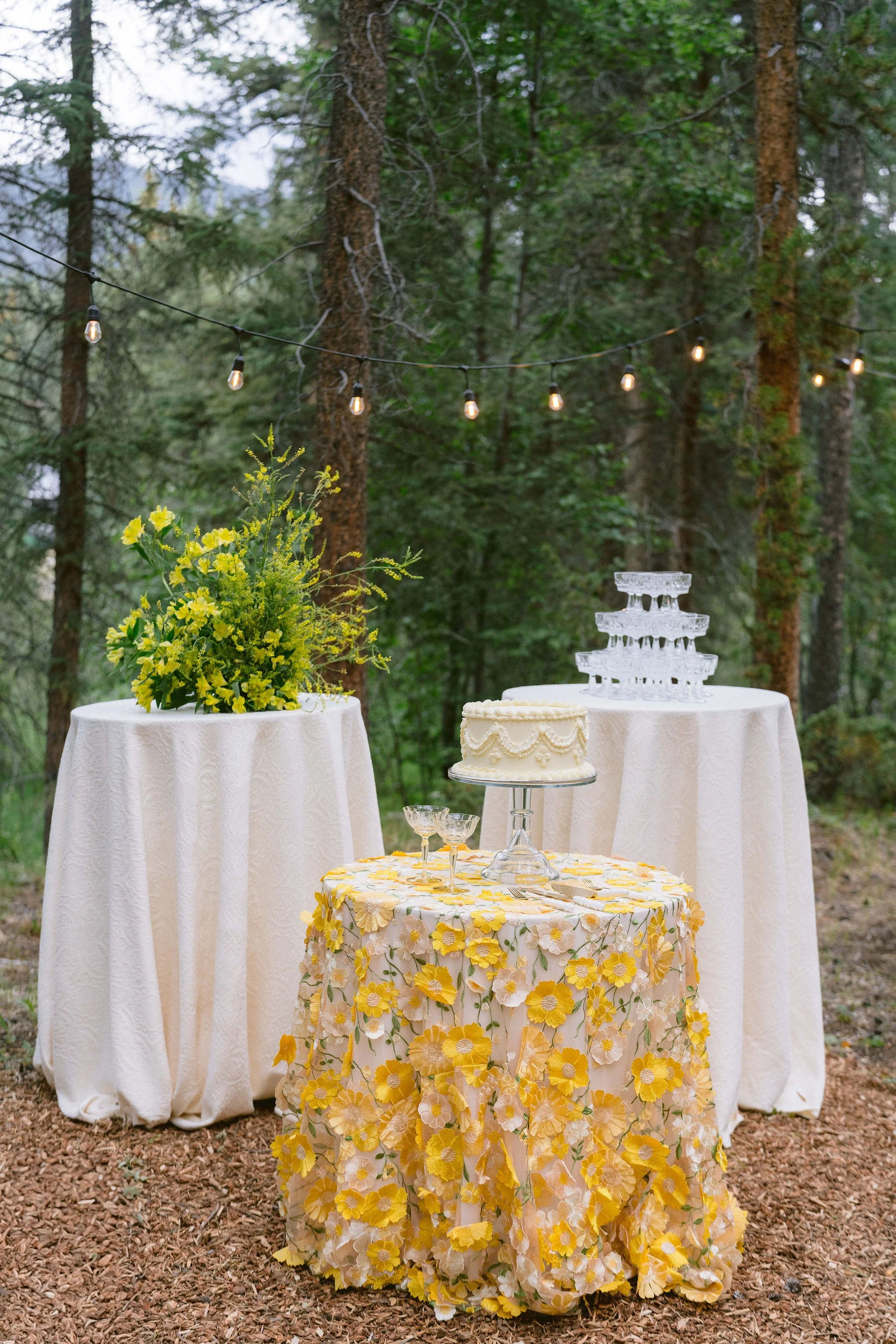 yellow vintage wedding cake on custom cocktail table with champagne tower in the background