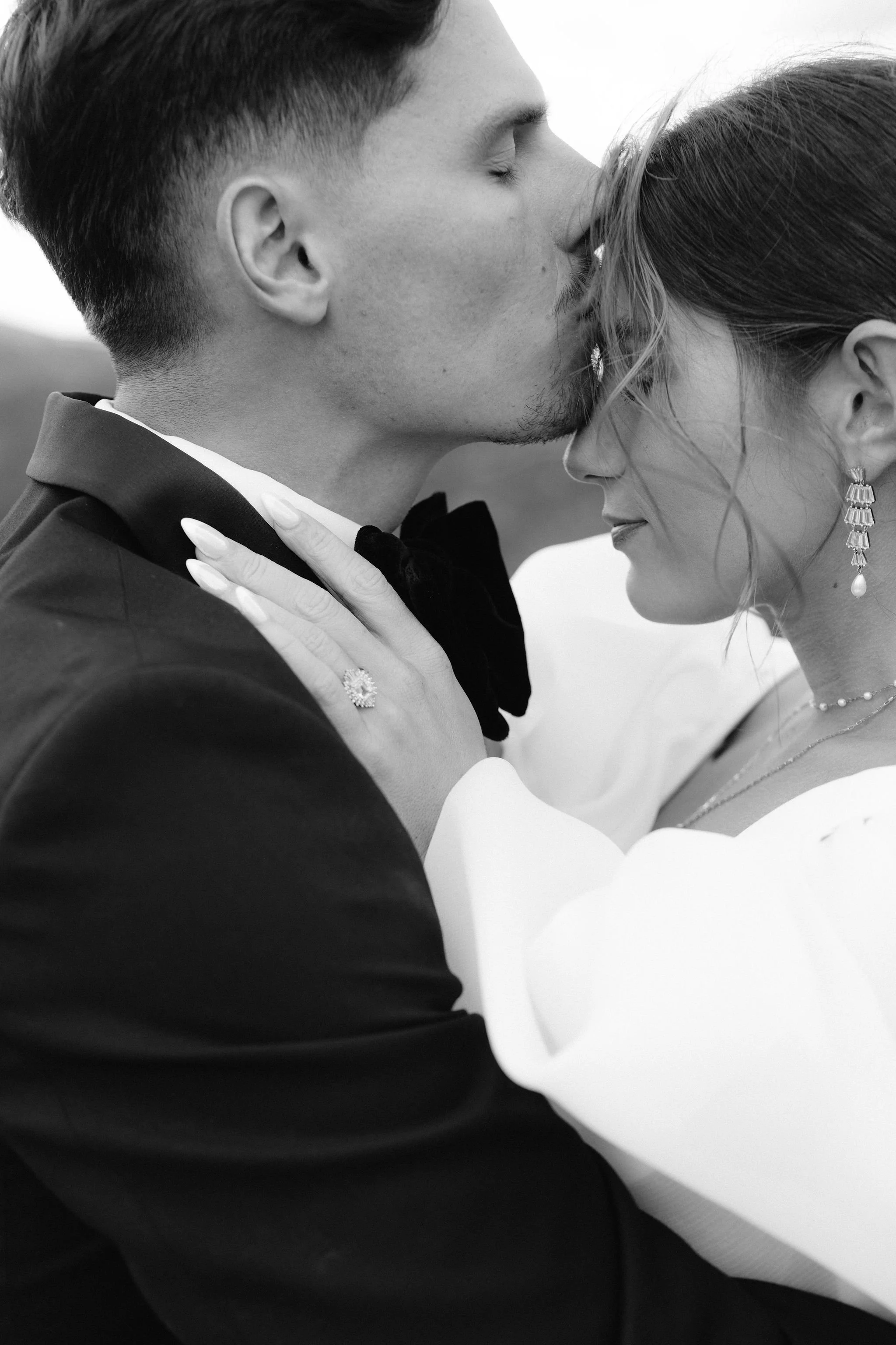 groom kisses brides forehead in black and white