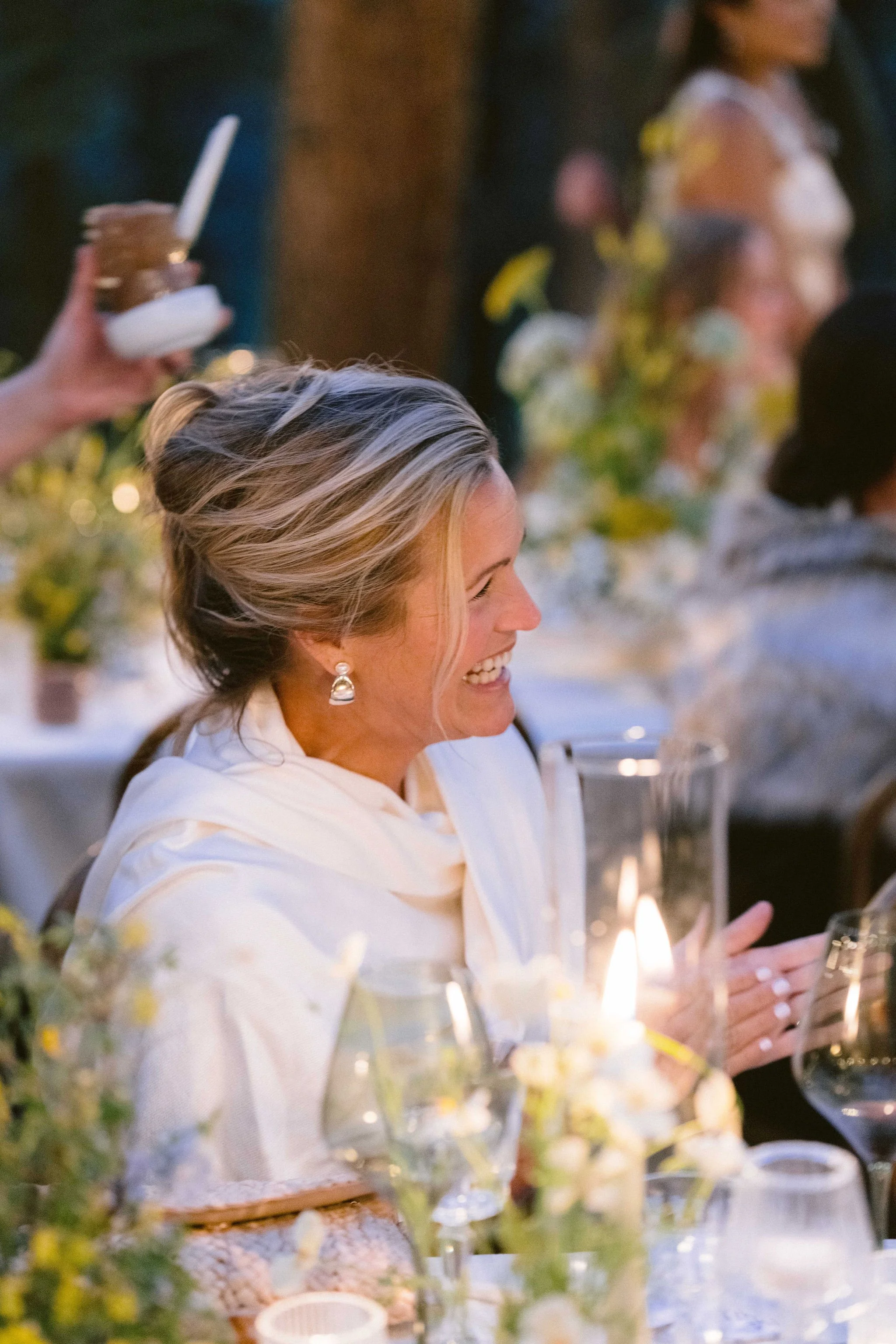 guest smiles and claps her hands illuminated by the candlite