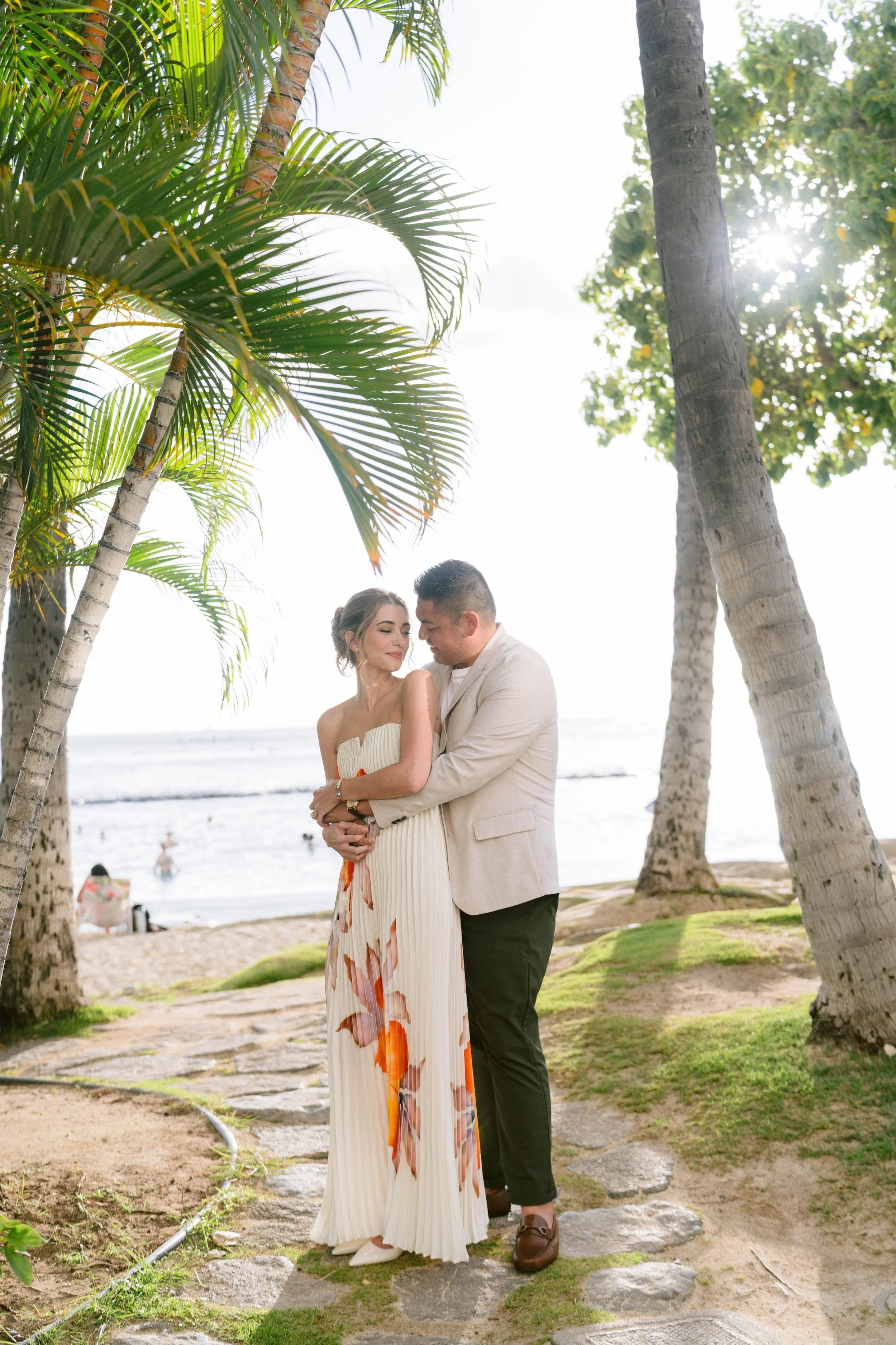 bride and groom at their wedding welcome party cuddling arms around each other on wakiki beach