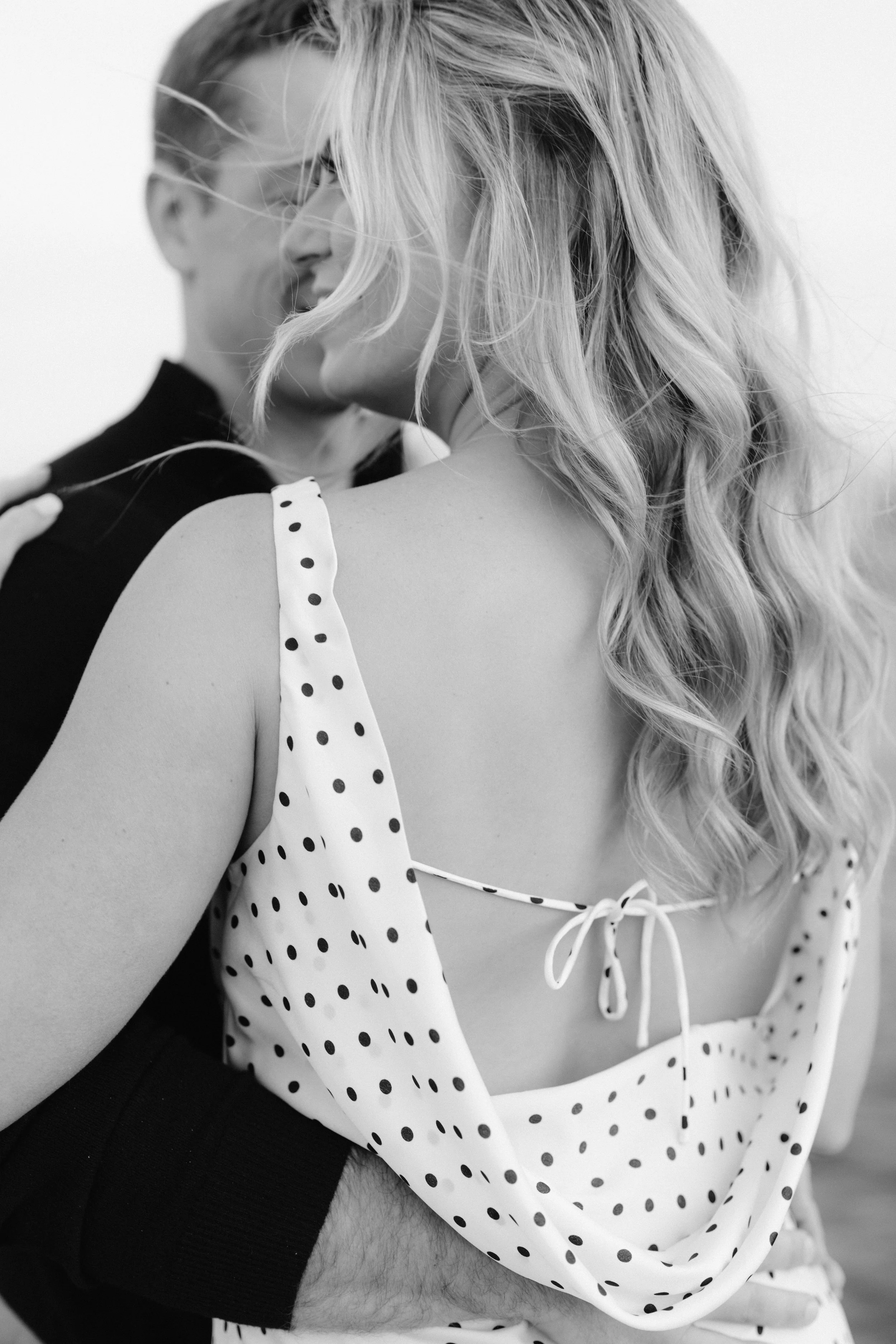 Couple with their arms around each other with fiancee in polka dot dress during chicago enagement photos at north avenue beach