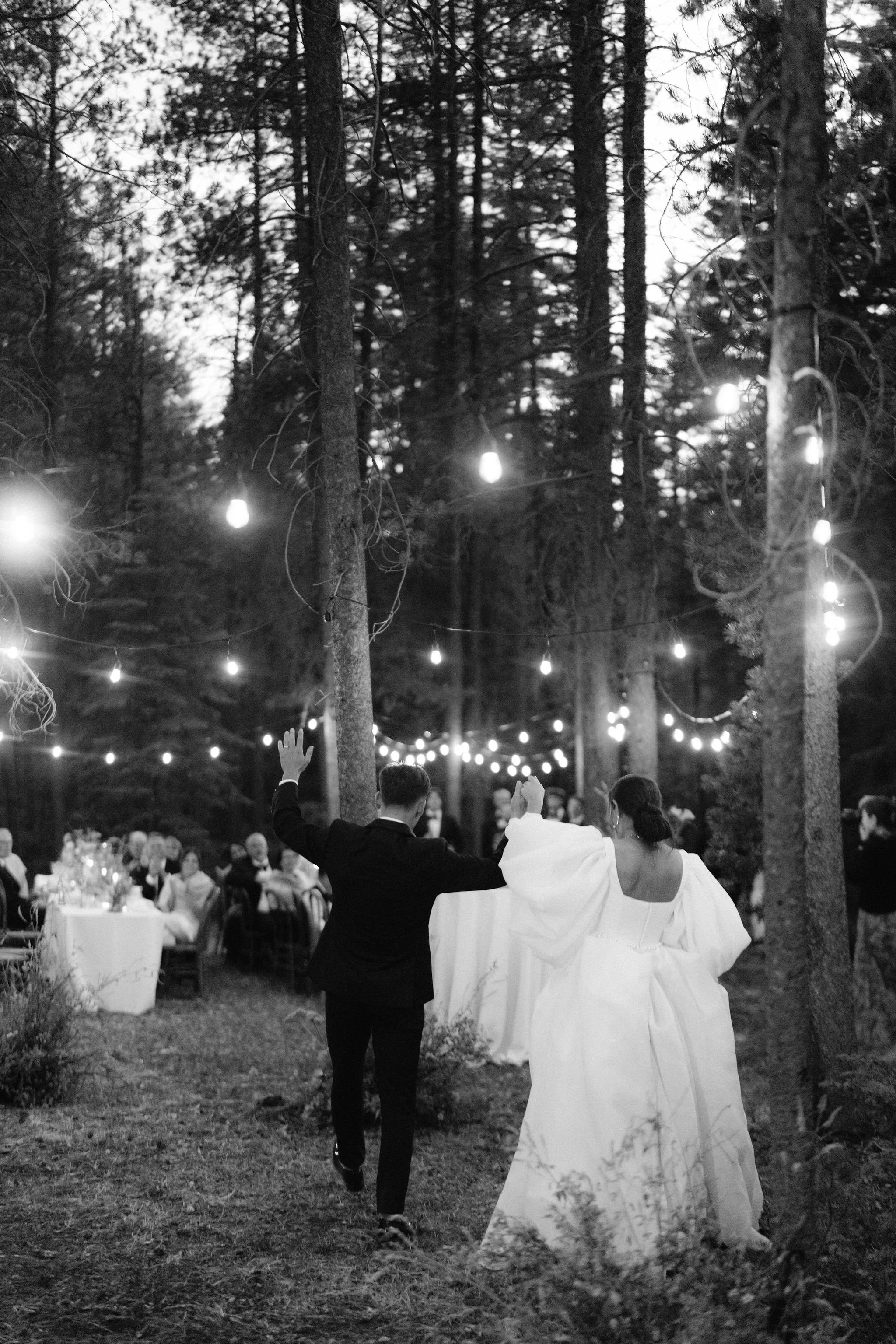bride and groom raise arms and celebrate their first dance while guests look on in the background