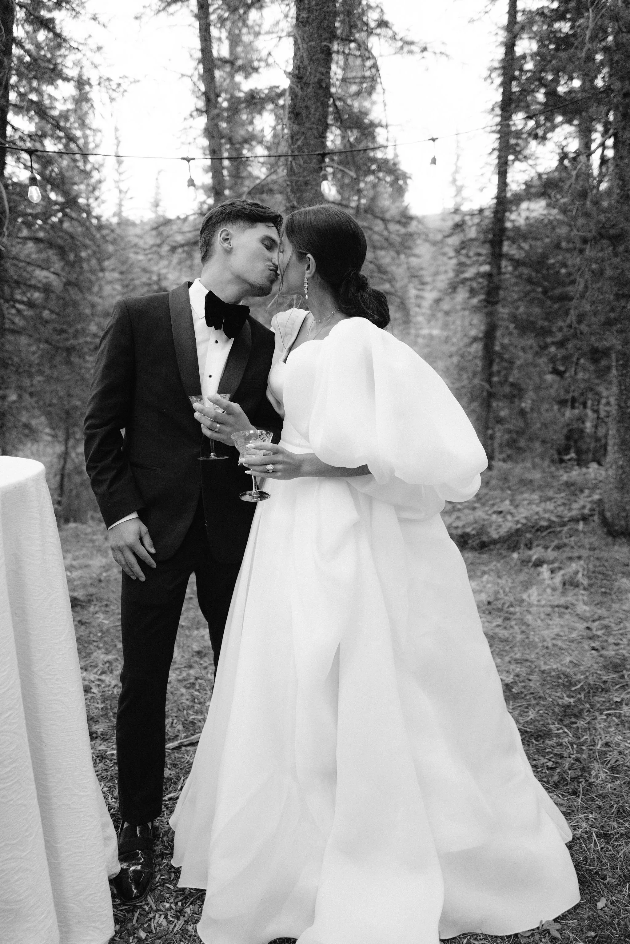 bride and groom kissing after cutting the cake and taking a drink of champagne