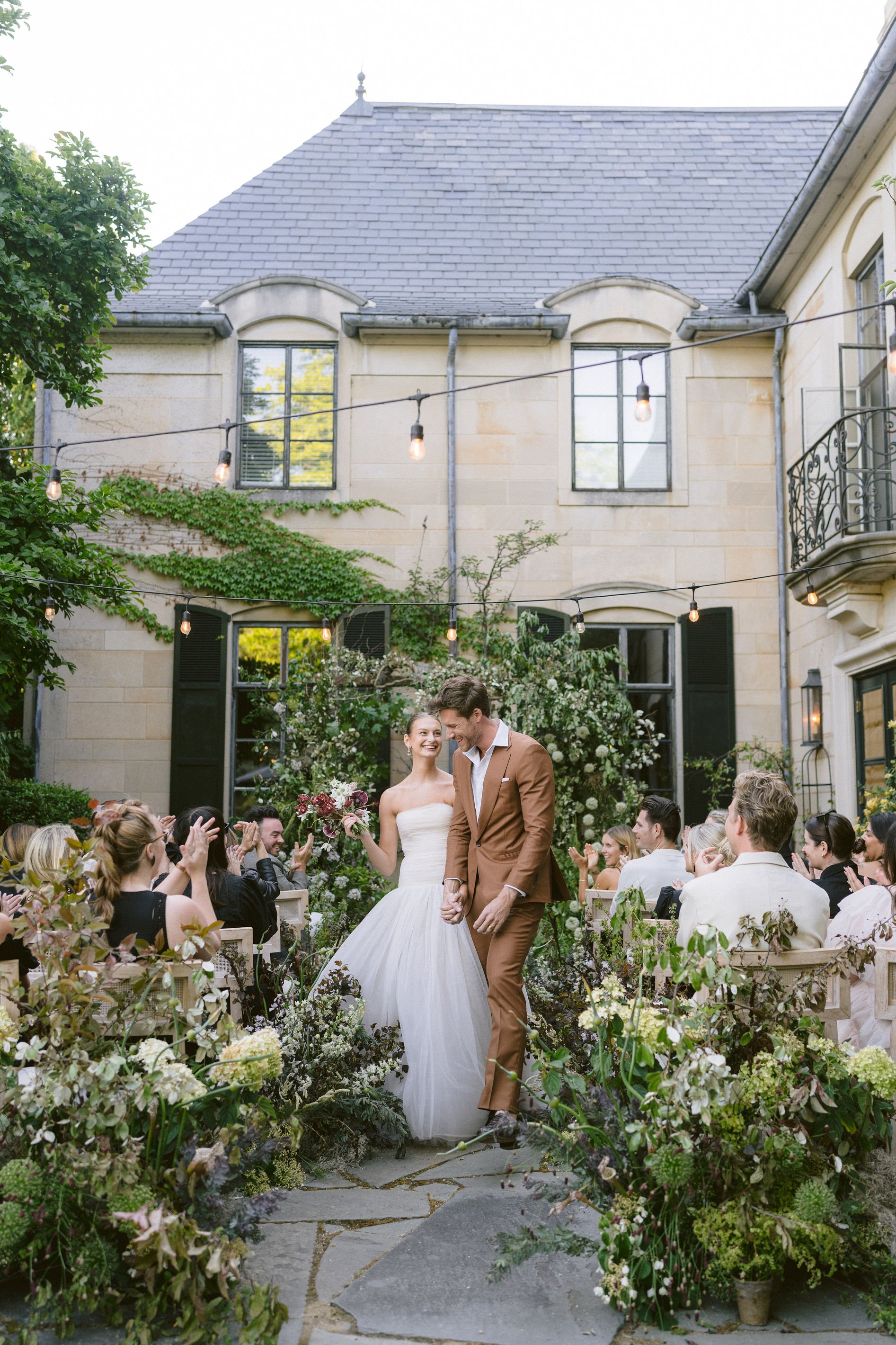 bride and groom recess down the aisle while friends and family cheer on the terrace at greencrest manor