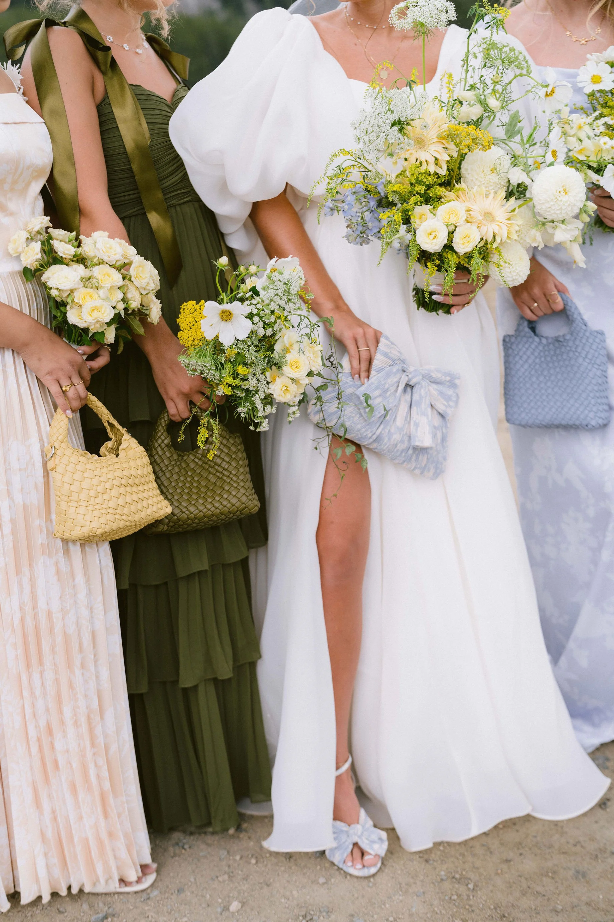 the bride and her bridesmaids with small purses and bouquets that correspond to the color of their dresses
