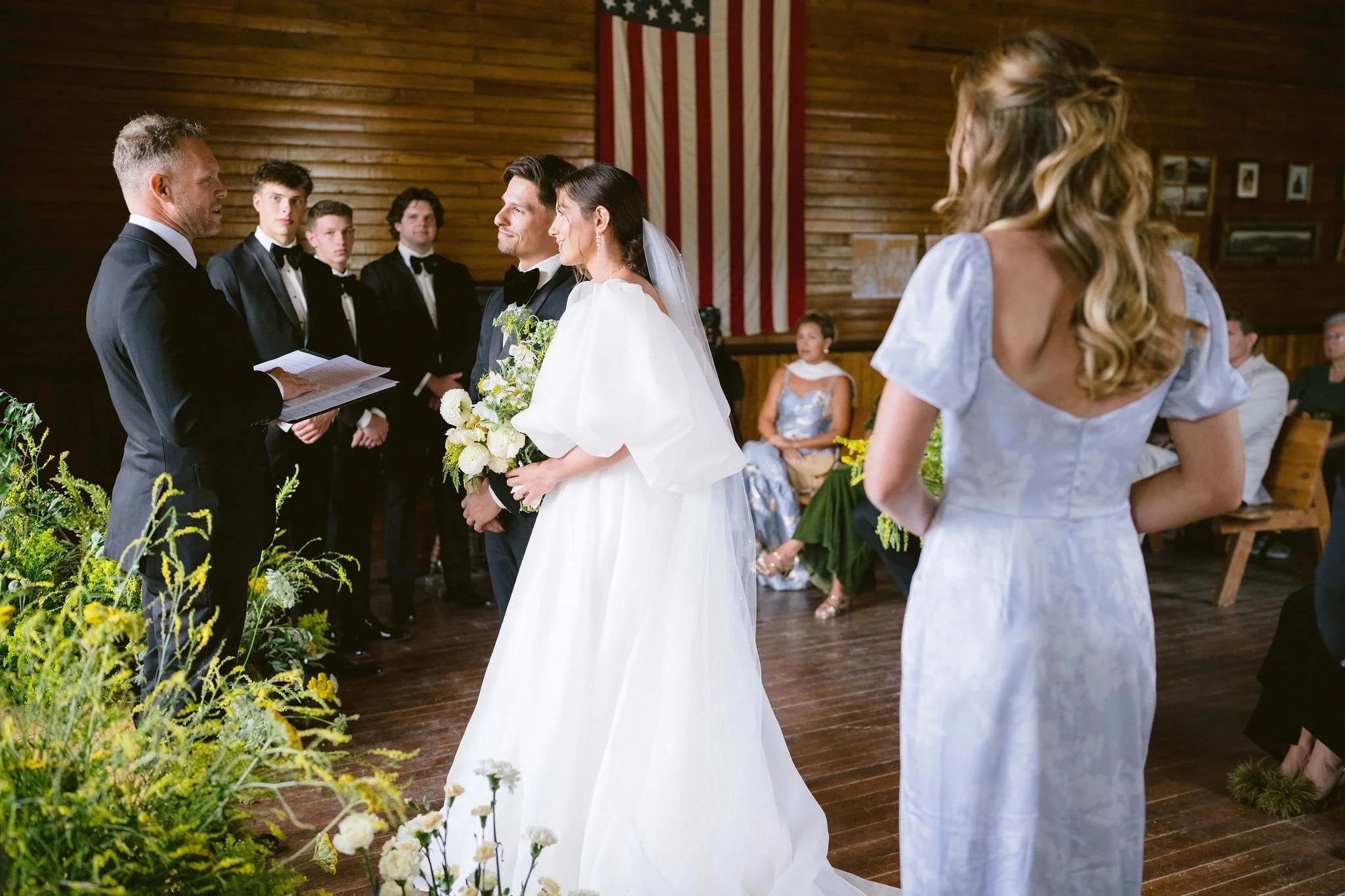 bride and groom at the front of the church during the ceremony with their families looking on