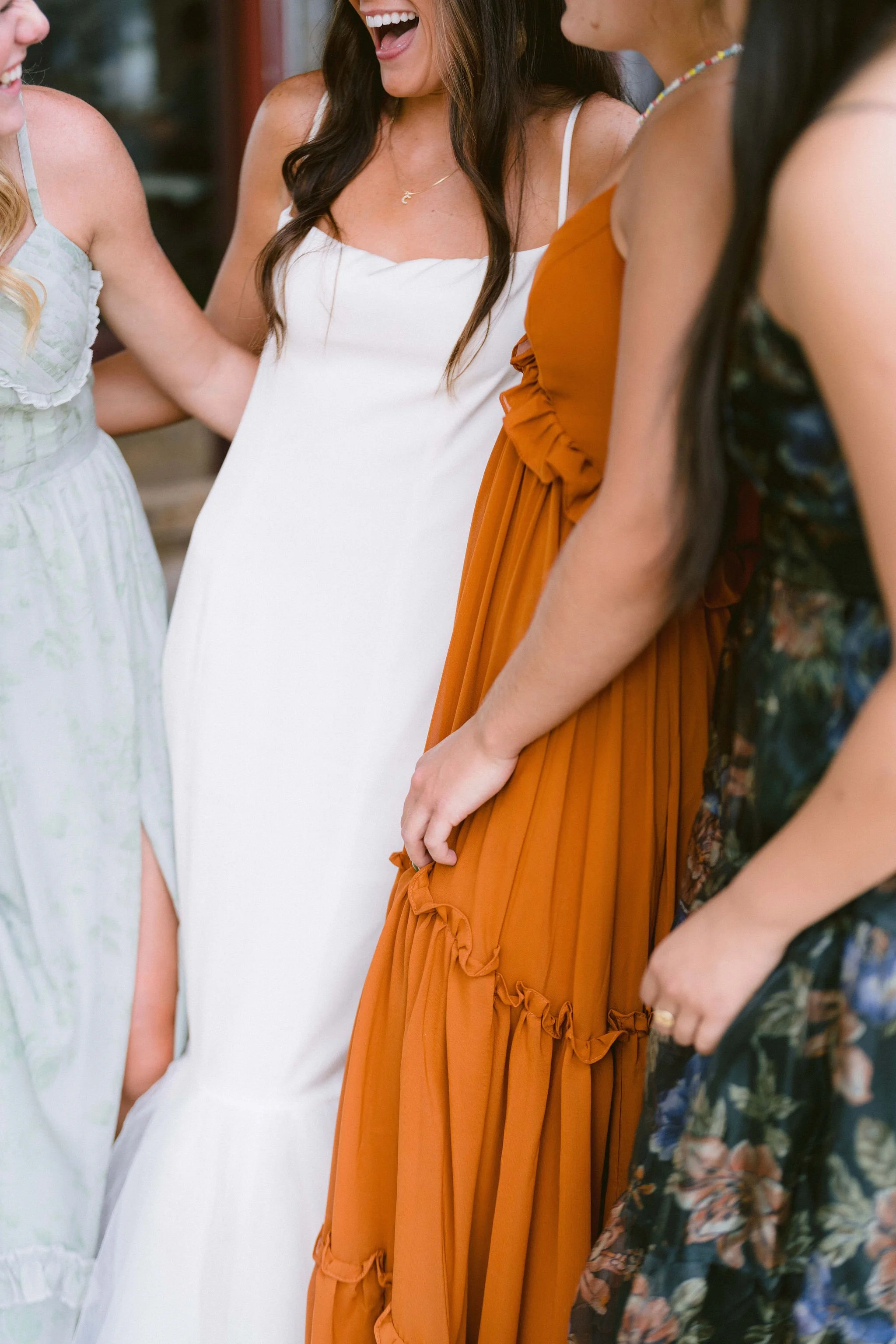 bride with her bridesmaids in colorful dresses outside the pitkin hotel at wedding welcome party