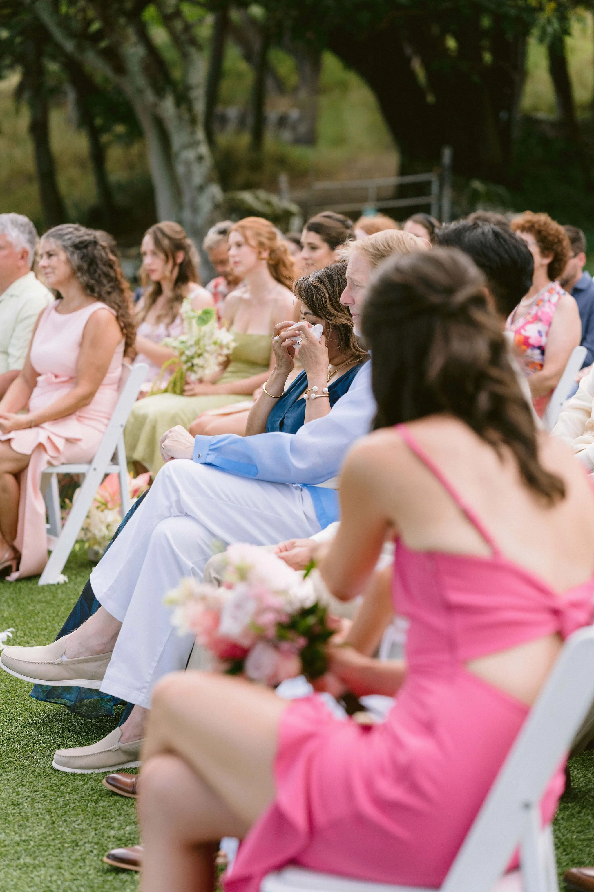 mother of the groom wipes tears from her eyes while watching vow exchange