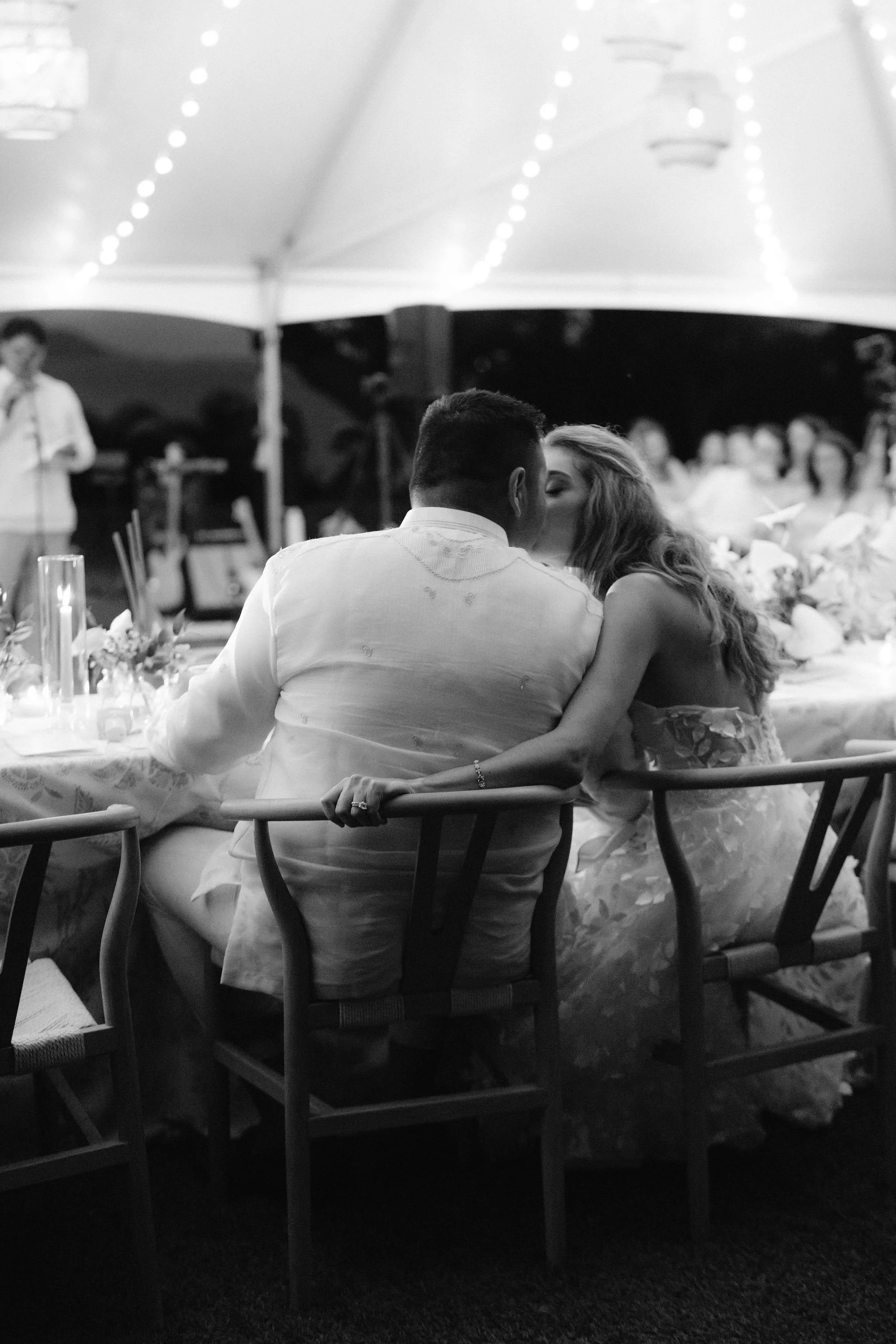 bride and groom exchange a kiss over their chairs at their wedding reception