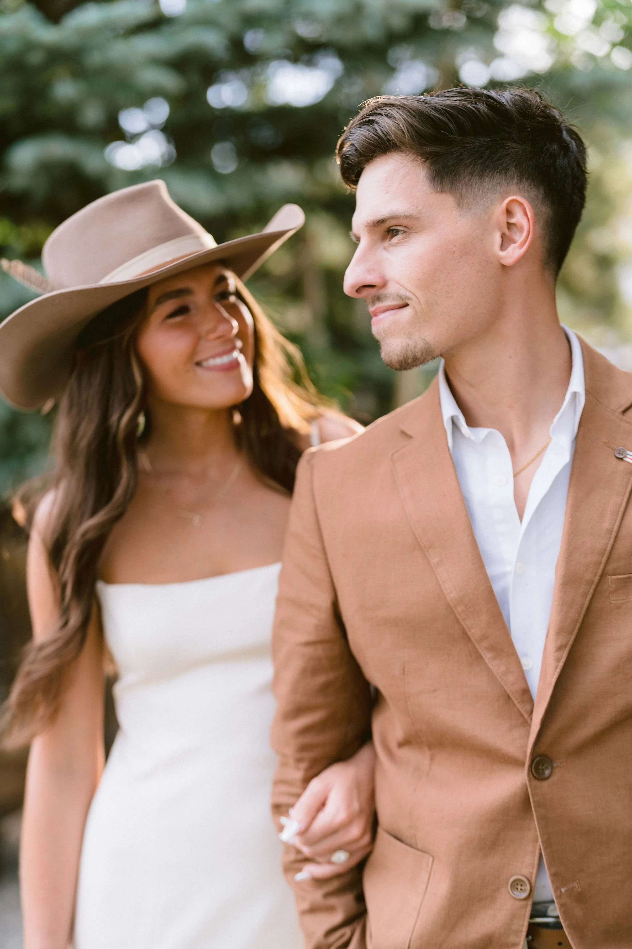 bride in cowboy hat looks at groom as he looks over his shoulder
