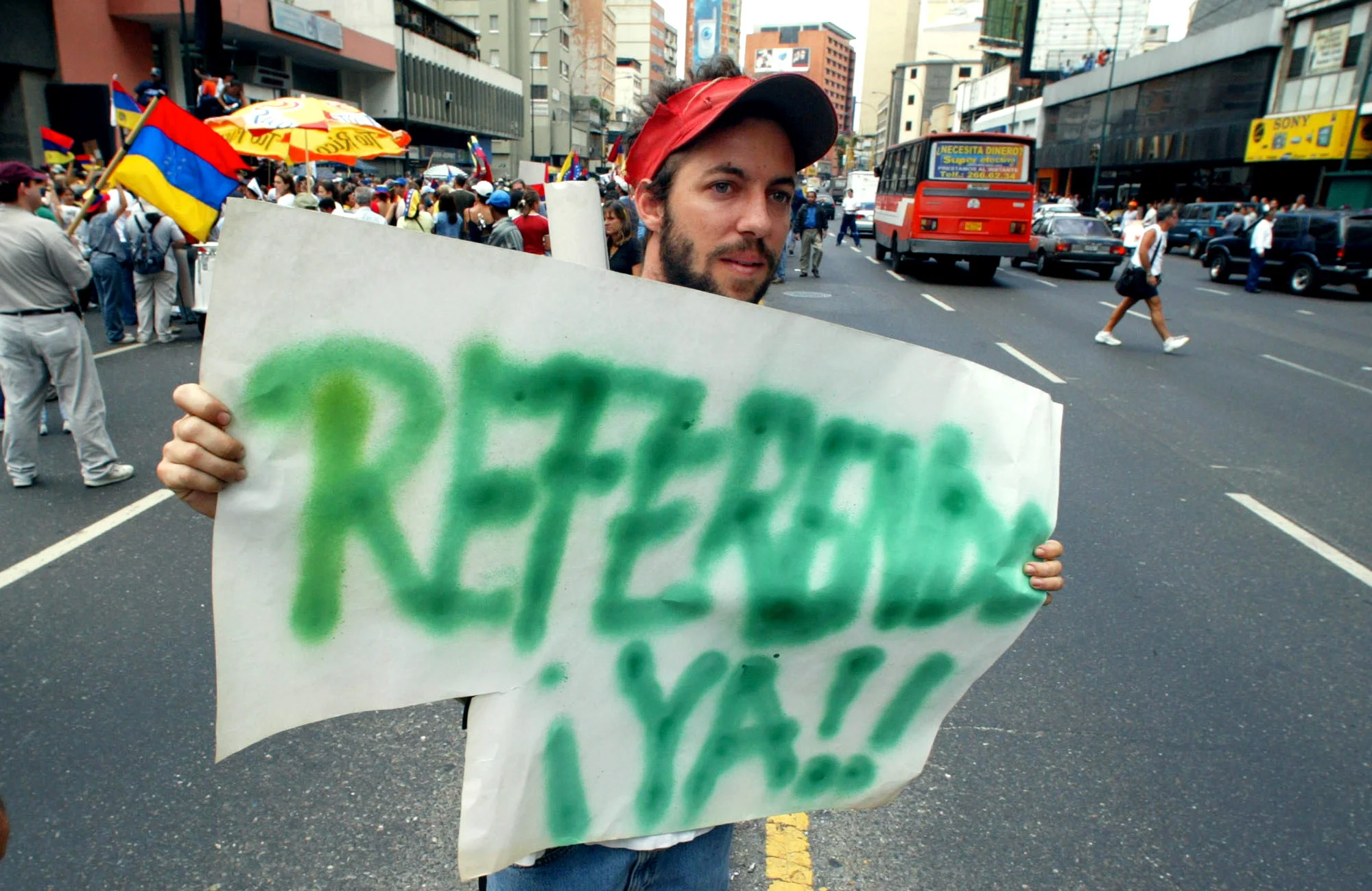  An anti-President Hugo Chavez protester holds a sign reading "Referendum already" at a protest during rioting that erupted after election officials denied a petition for a vote to recall President Hugo Chavez in Caracas, Venezuela, 2004. 