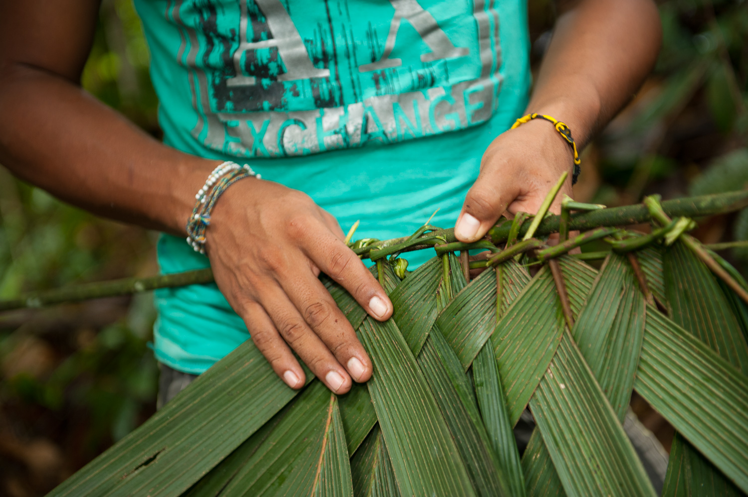 Hernando Tapullima, who leads eco-tours through the Amazonian village of Puerto Prado, demonstrates the process for weaving leaves to use in homes.