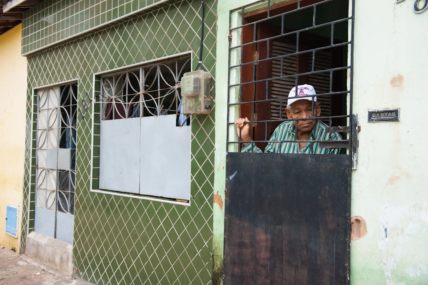 An elderly man who had been evicted from his home on the ocean looks out from his new home in the favela (slum) Poco da Draga, which may be demolished for a parking lot.