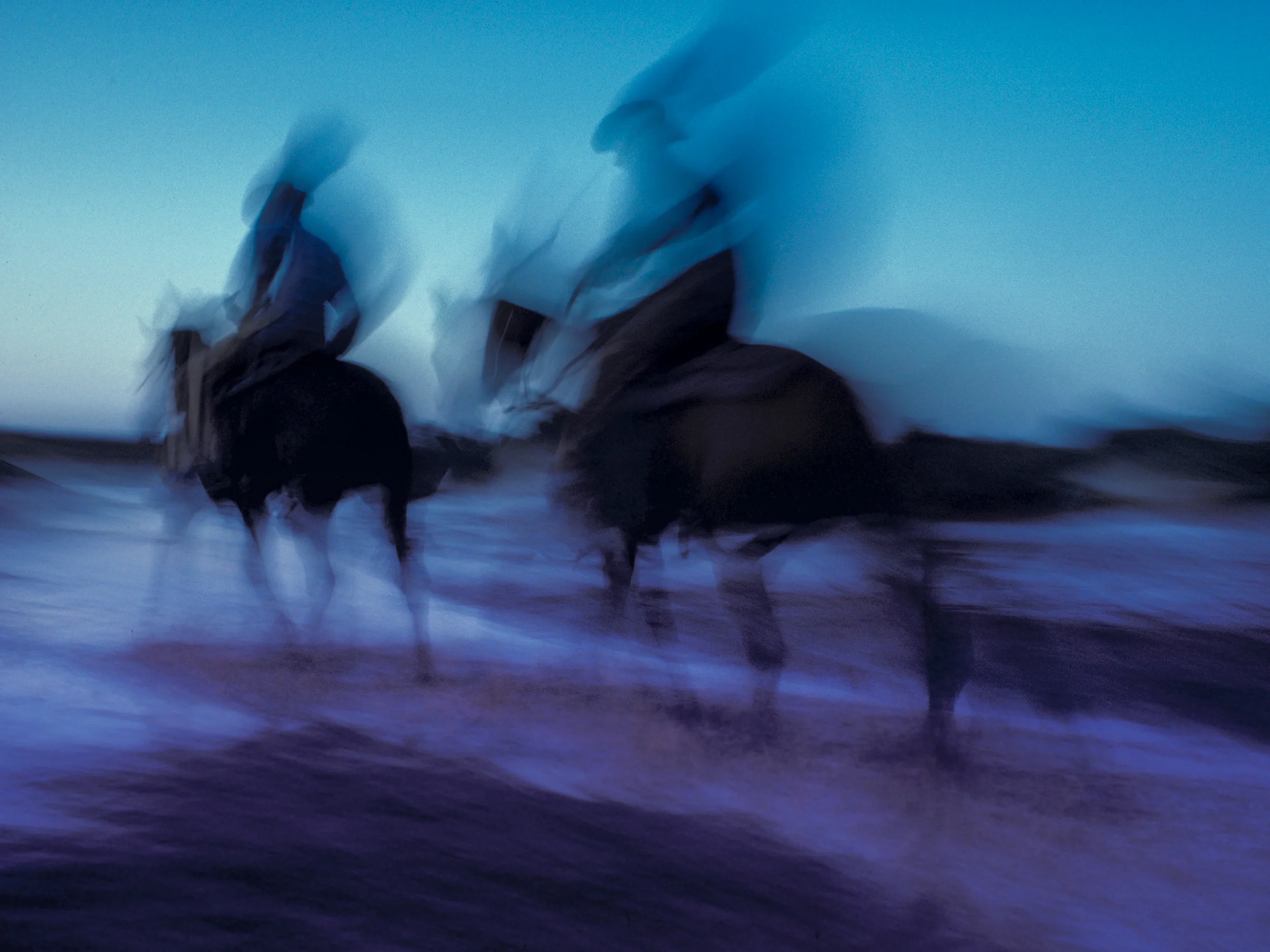 Cowboys on horseback ride through creek crossing at dusk. Copyright © Kipp Baker, All rights reserved