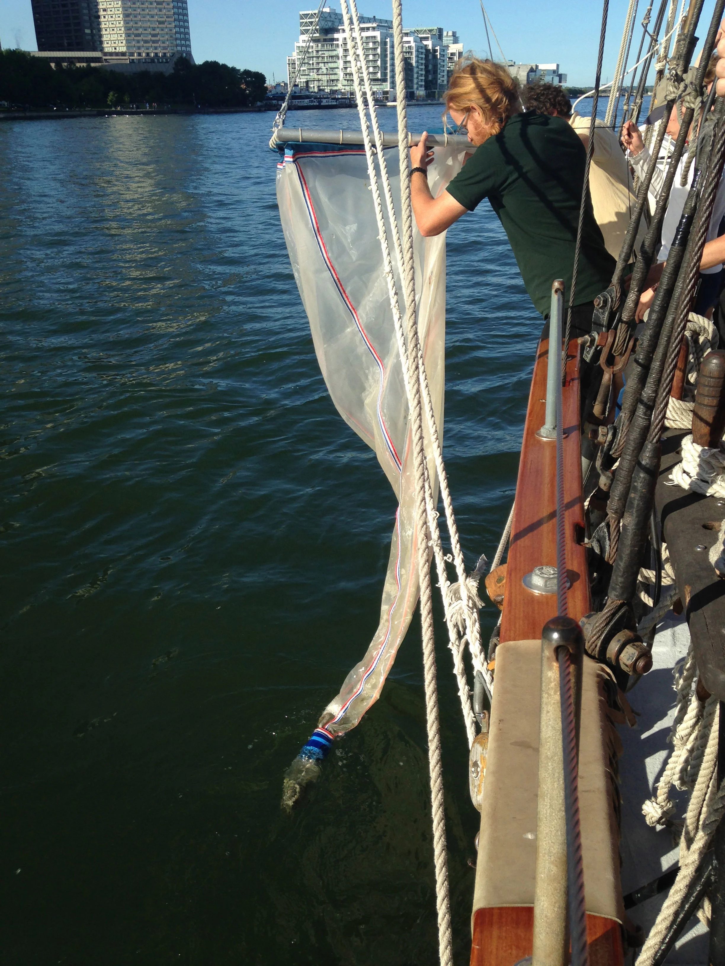 Master Patrick Shore, who manages the microplastics testing program this summer on the TS Playfair , lowers the net. (Photo via Lake Ontario Waterkeeper)