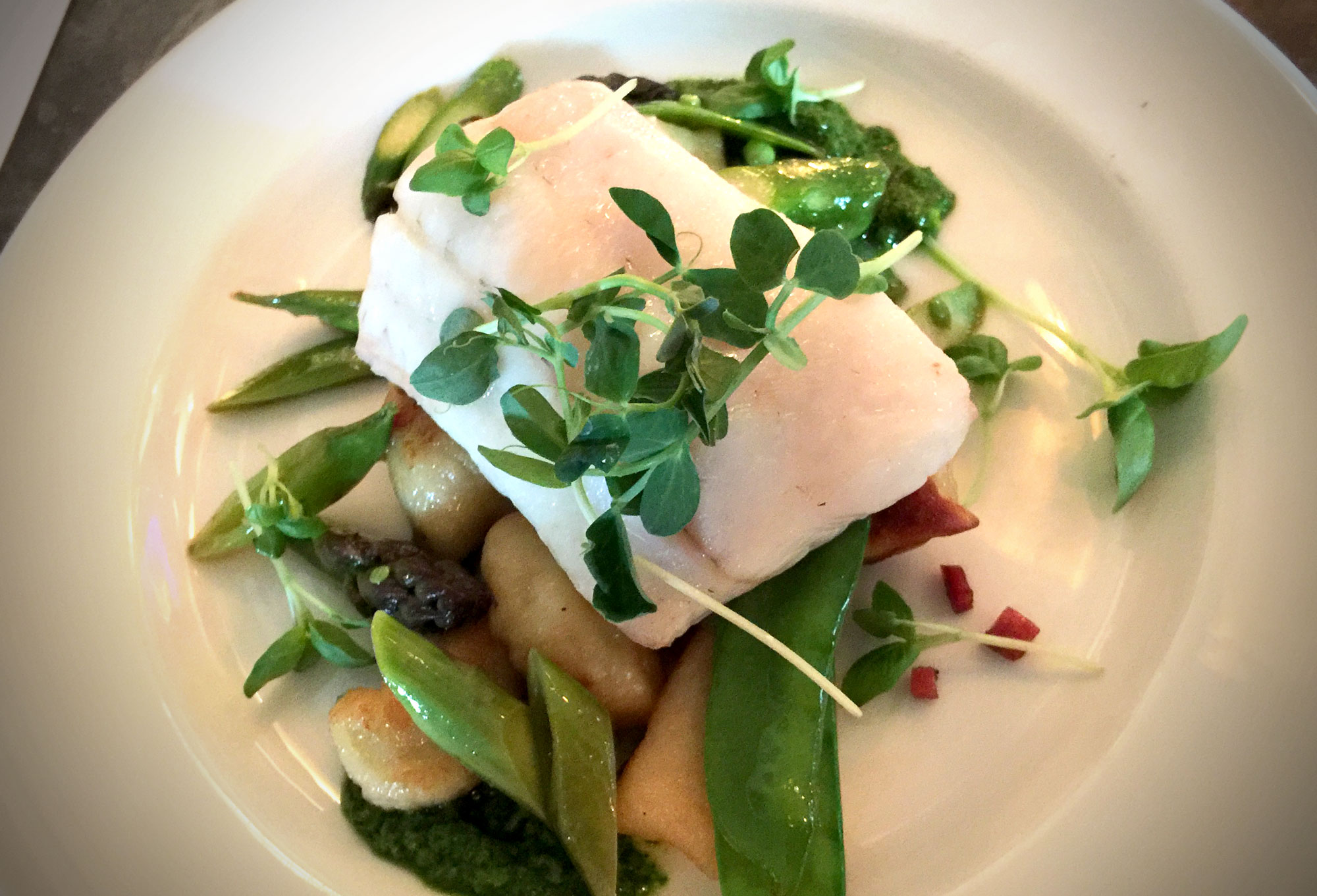 The main course: Baked walleye on lomo-fried potato dumpling, sugar snap peas, roasted asparagus, and preserved lemon-ramp pesto. (Photo by Ruby Pajares)