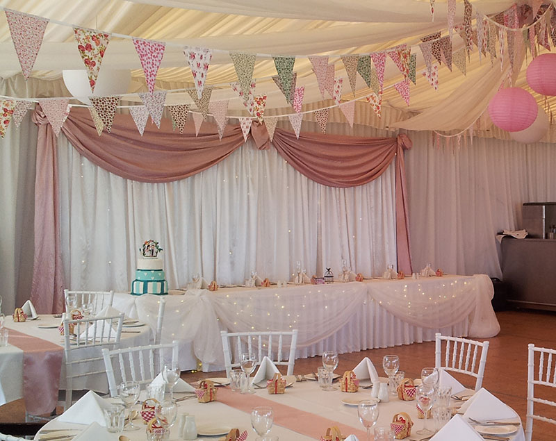 A sweet white backdrop with a pink fabric swag. 