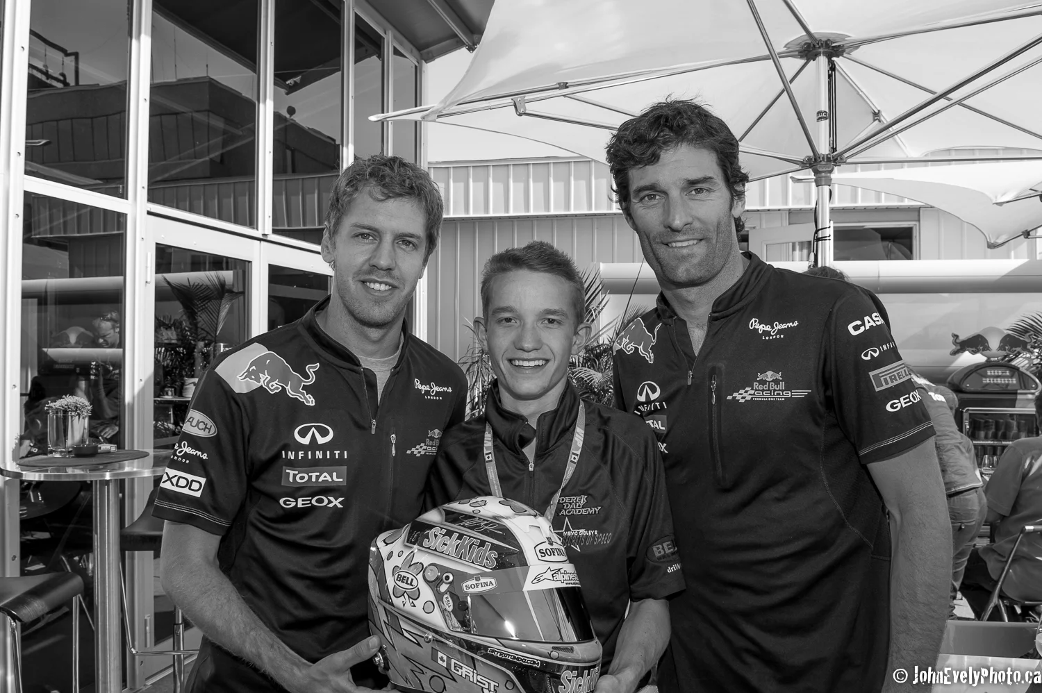 Sebastien Vettel and Mark Webber with young driver in the Red Bull Paddock.
