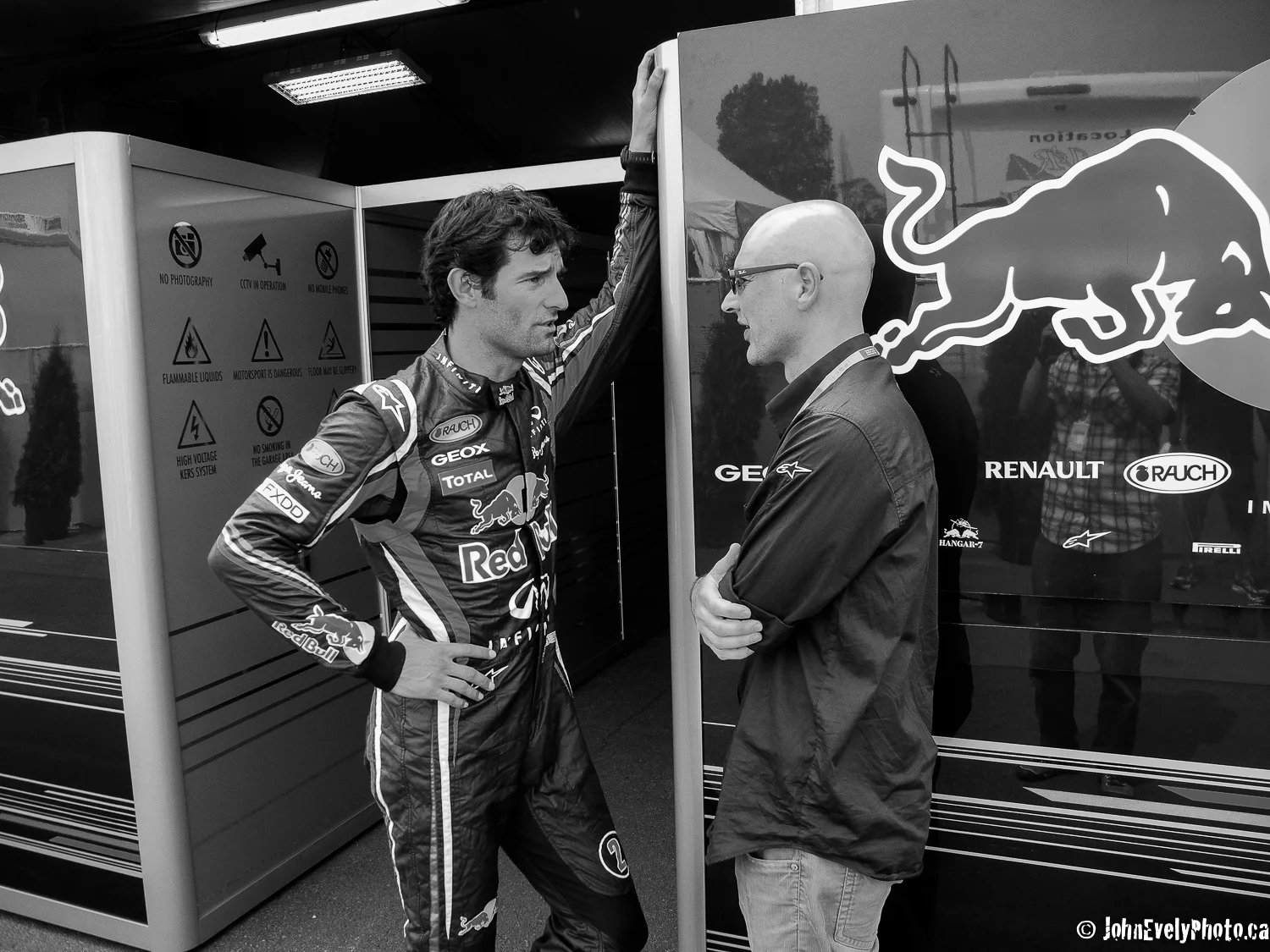 Mark Webber talks with his race engineer in the Red Bull paddock.