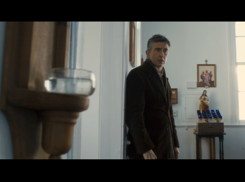 Screenshot: Martin standing inside St. Paul's Community Church where the production team added religious elements to turn it into a Catholic church, including the font of holy water featured in the foreground.