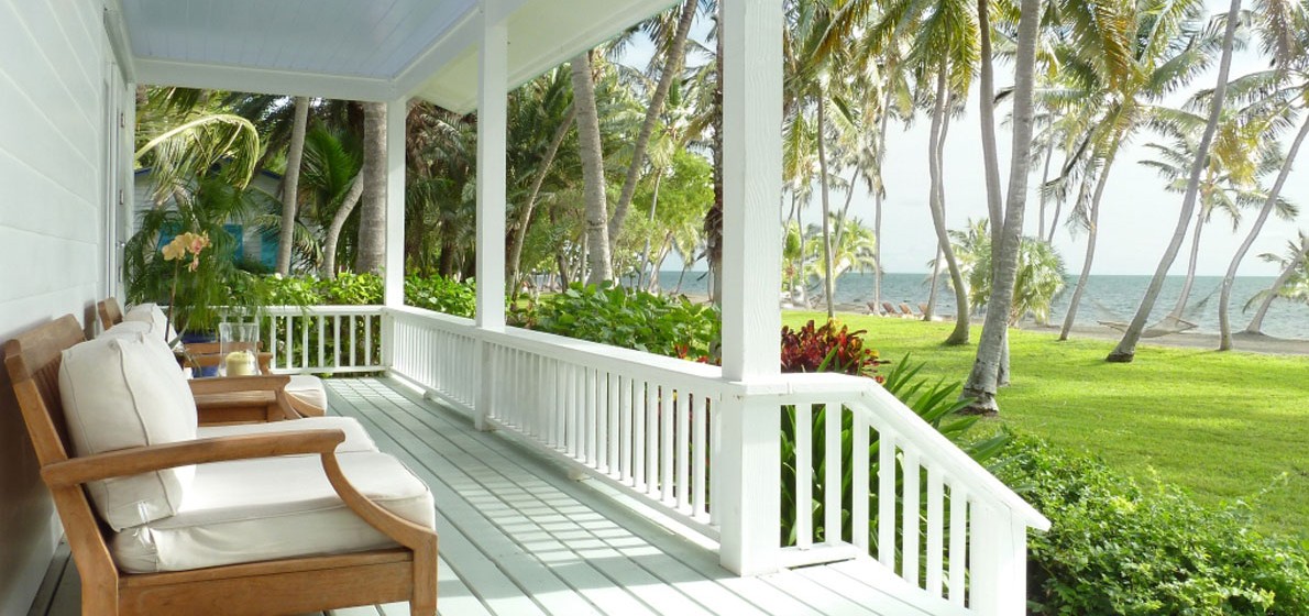 One of the distinctive cottage verandas of the Moorings Village & Spa with views of the private, palm-lined beach - image via the resort's website .