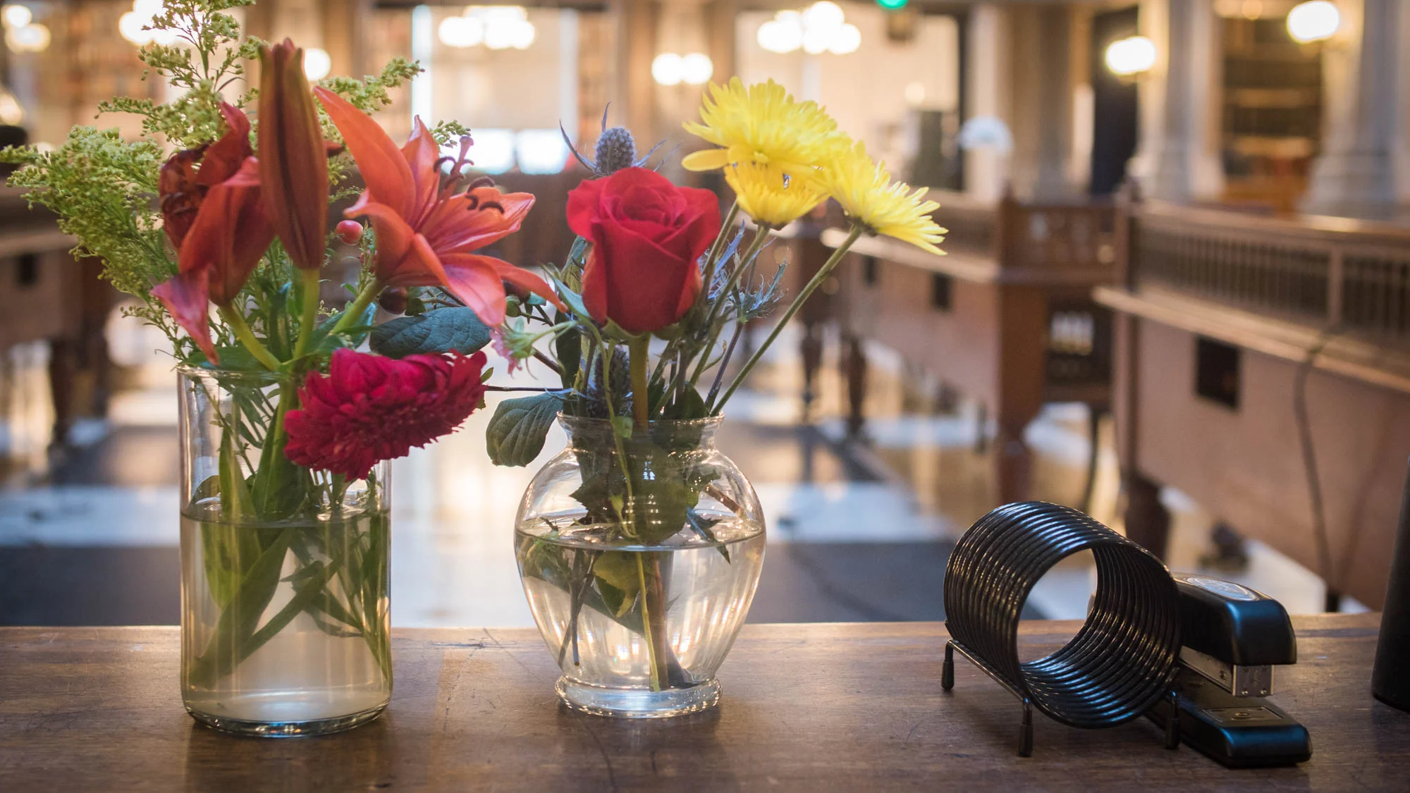 On some of the desks in the George Peabody Library, there are vases of fresh flowers.