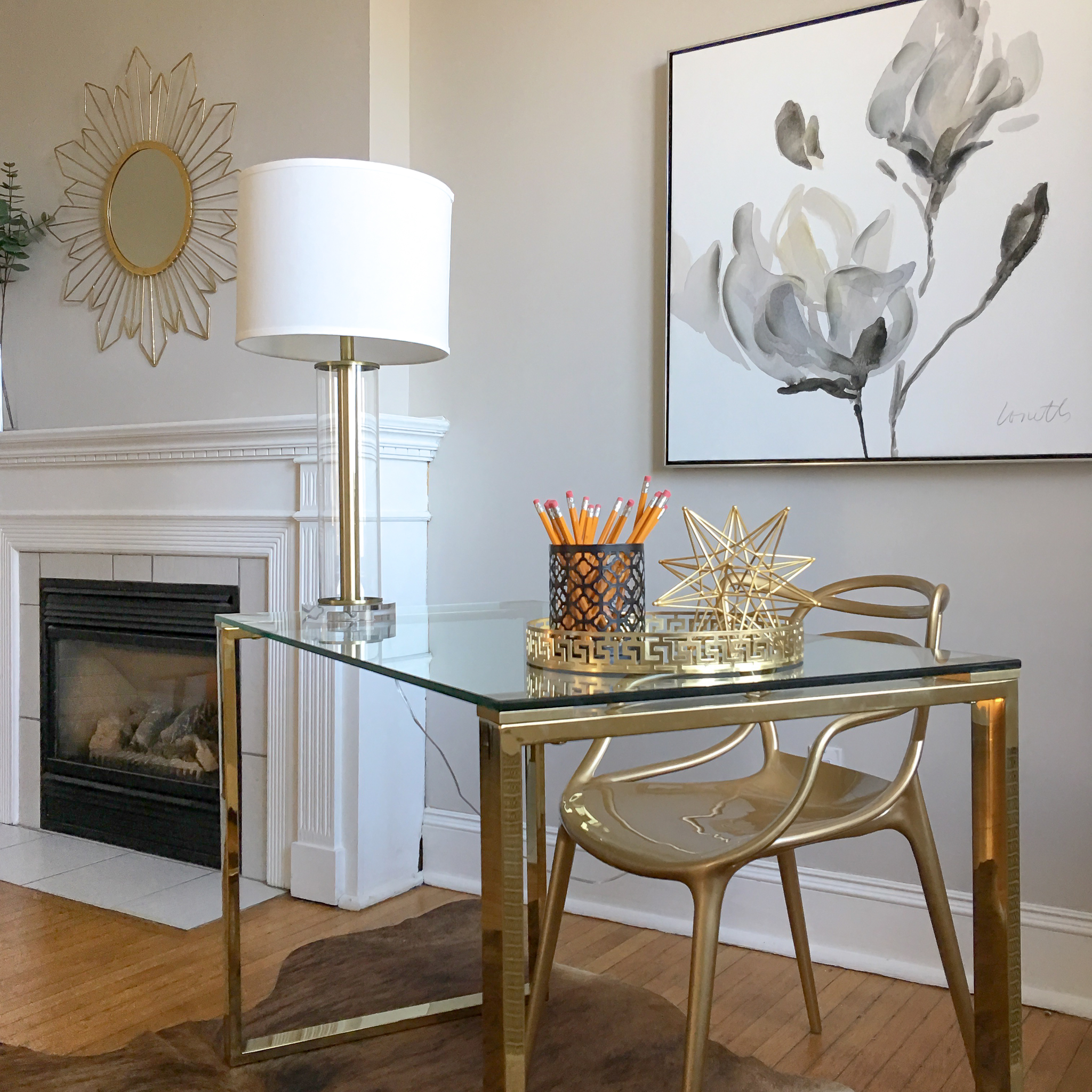 Luxury home staging in Aurora. Gold and glass desk paired with neutral statement art.