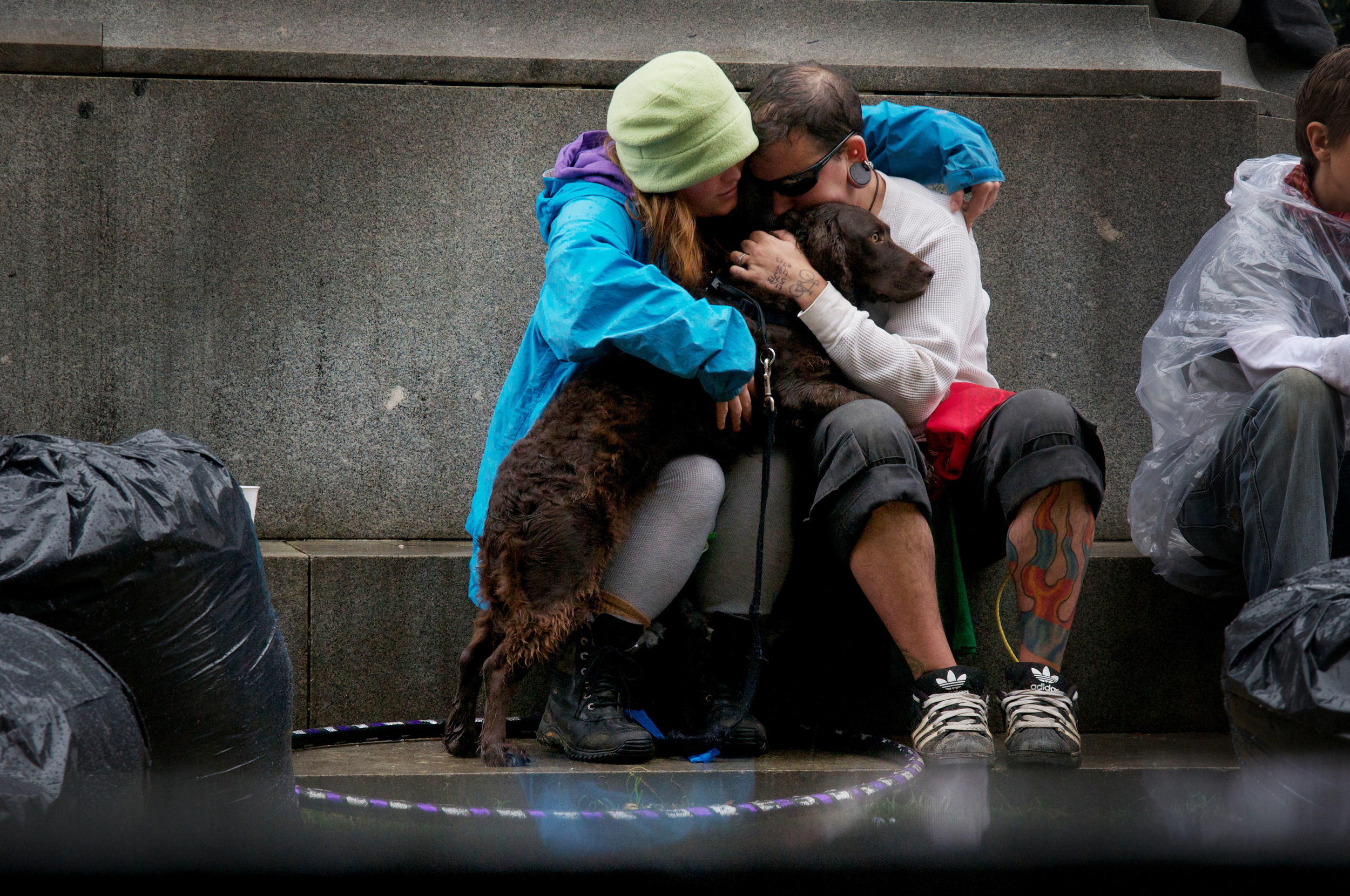 A couple and their dog huddle on a rainy day under McPherson Square statue during Occupy D.C., Washington, D.C.