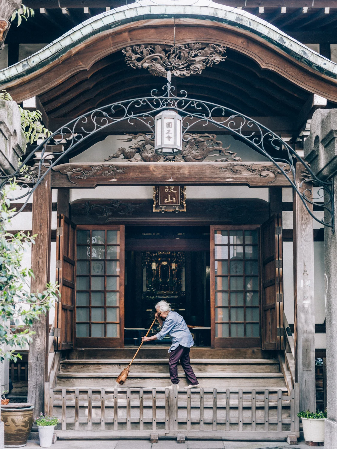 A woman sweeping the steps of her temple - which looked like it no longer belonged, sandwiched between modern buildings and stalls near Tsukiji Fish Market.