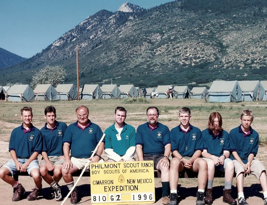 Jim (seated behind the sign to the right) and his crew before backpacking over 50 miles in the Sangre De Cristo mountains at Philmont Scout Ranch near Cimarron, New Mexico, in August 1996.