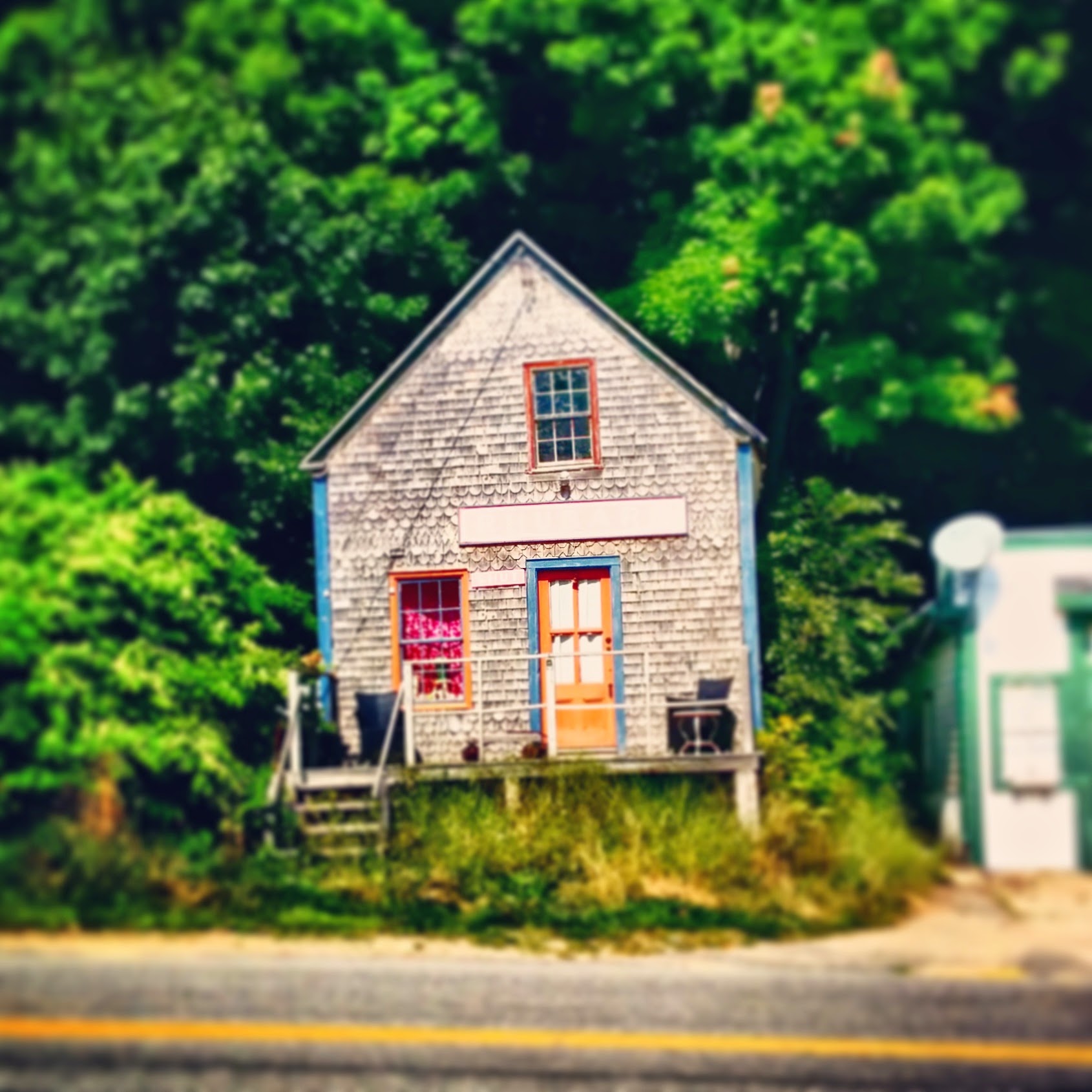 Just a colorful small house spotted on the side of the road in Maine. Sign above the door reads "RHUBARB".