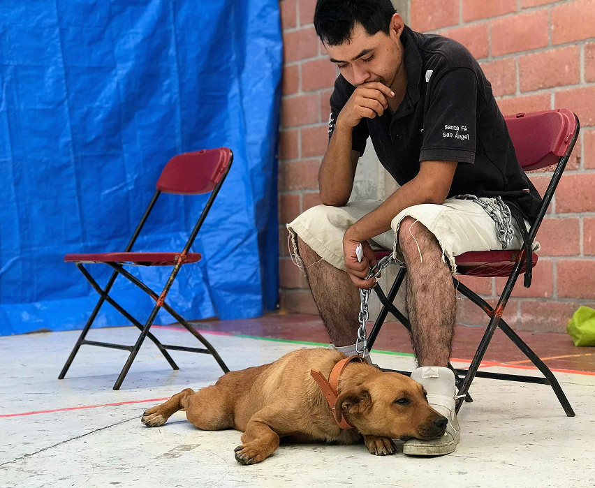 A man sits in the waiting room with his dog before spaying an neutering procedure.
