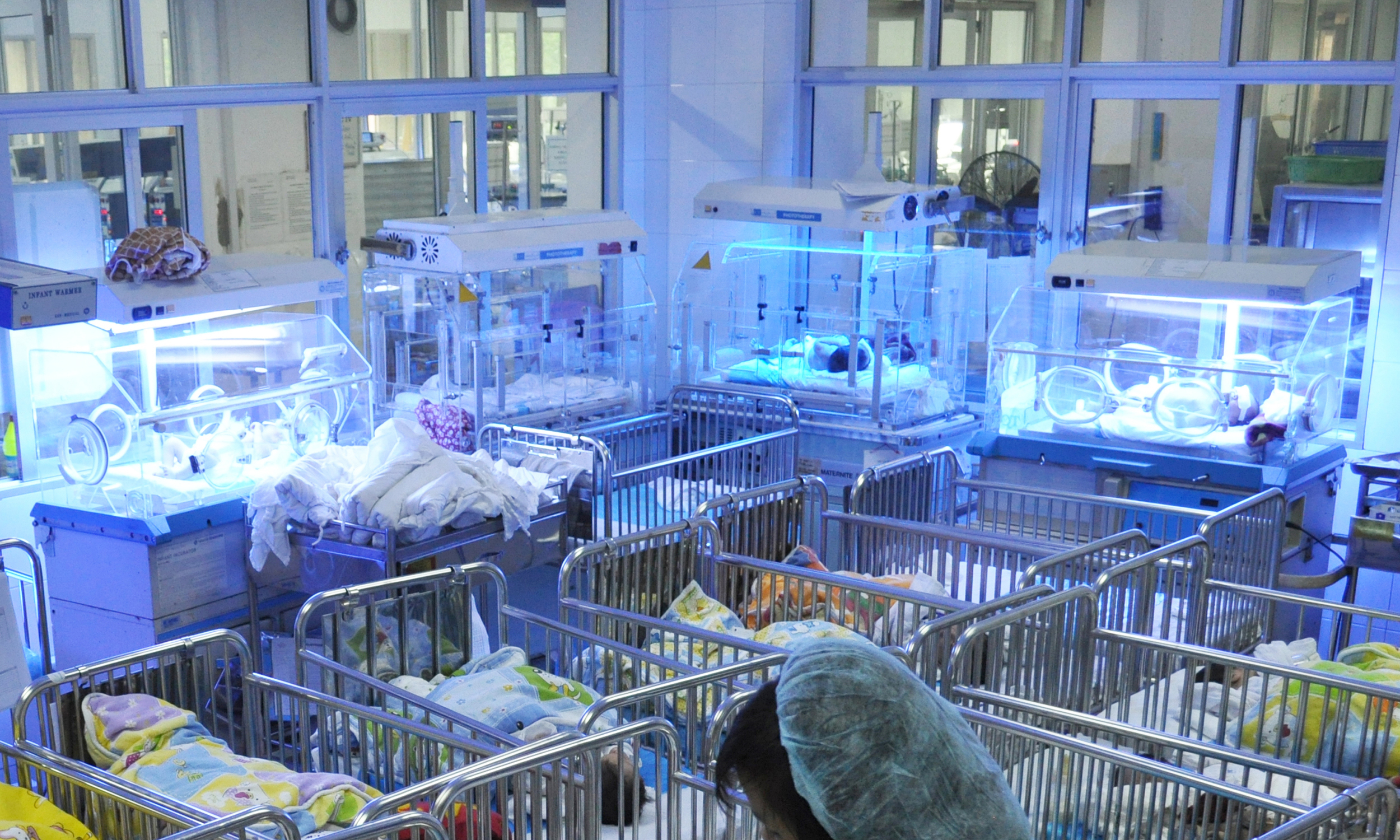 Don’t be fooled by the phototherapy lamps shining from above; the four nonworking incubators that sit along the walls are used only as hard to clean beds for the well-baby room at a national hospital in Vietnam. 