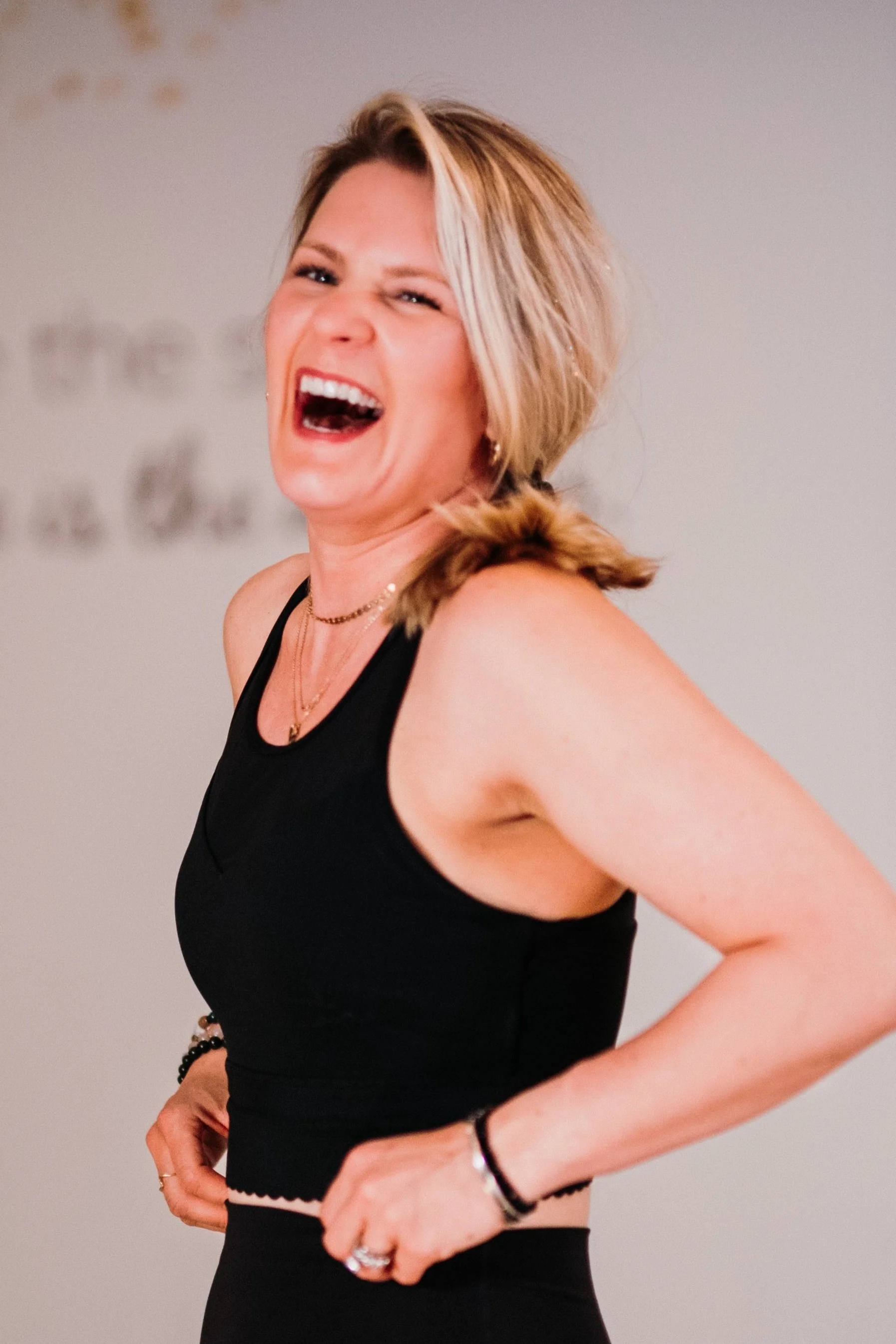 Katie Randazzo-Erway, Women's Fitness and Postpartum coach, laughing and holding a kettlebell.