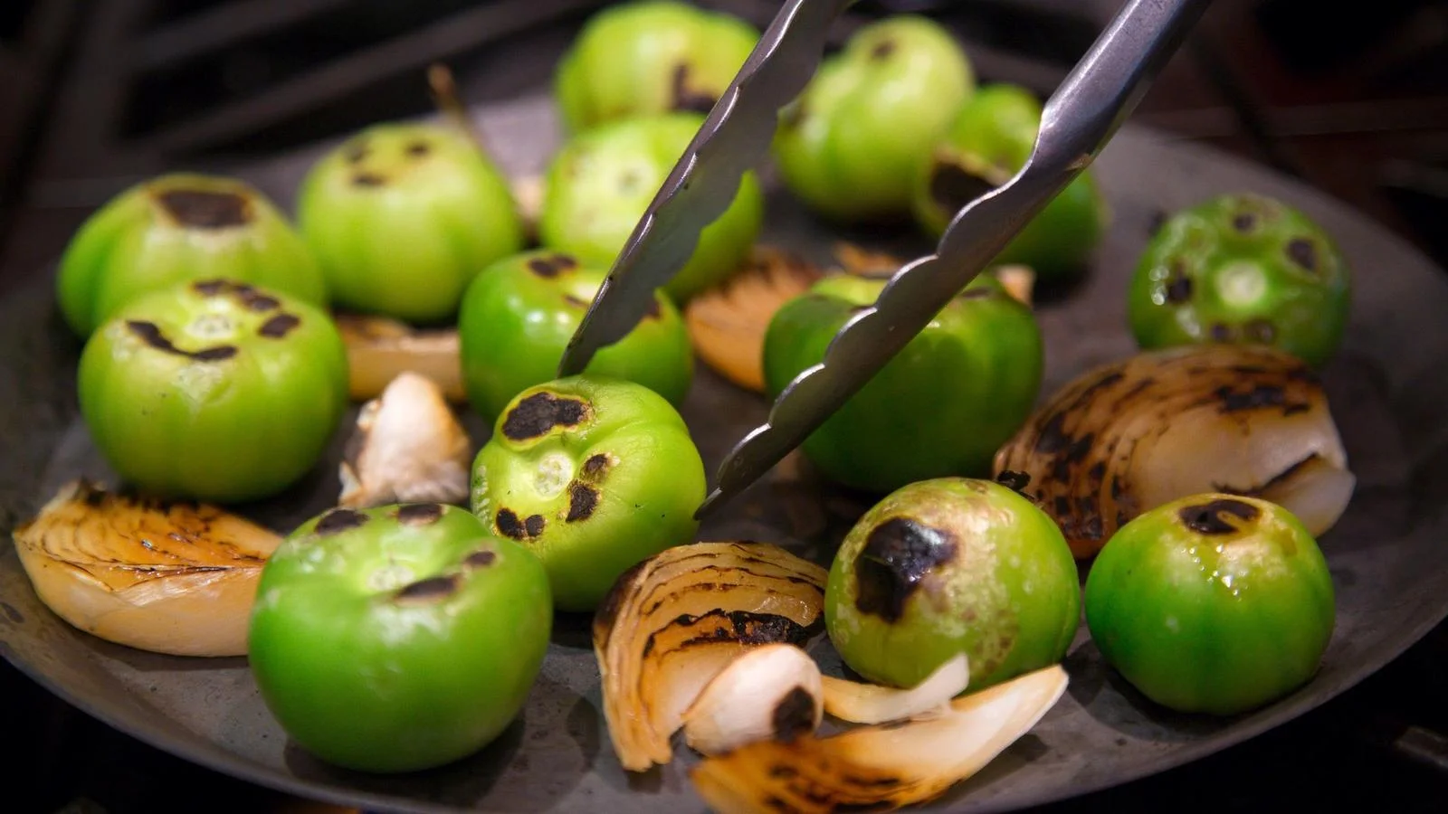 Dry roasting tomatillos, onion, and garlic on a comal
