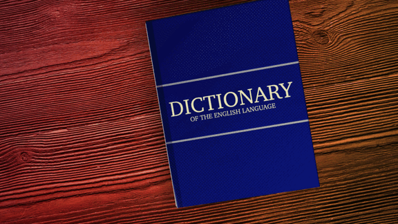 Blue dictionary titled 'Dictionary of the English Language' on a wooden surface.