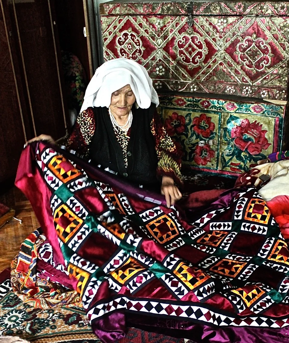 Tajikistan. Woman with quilt of velvet and silks