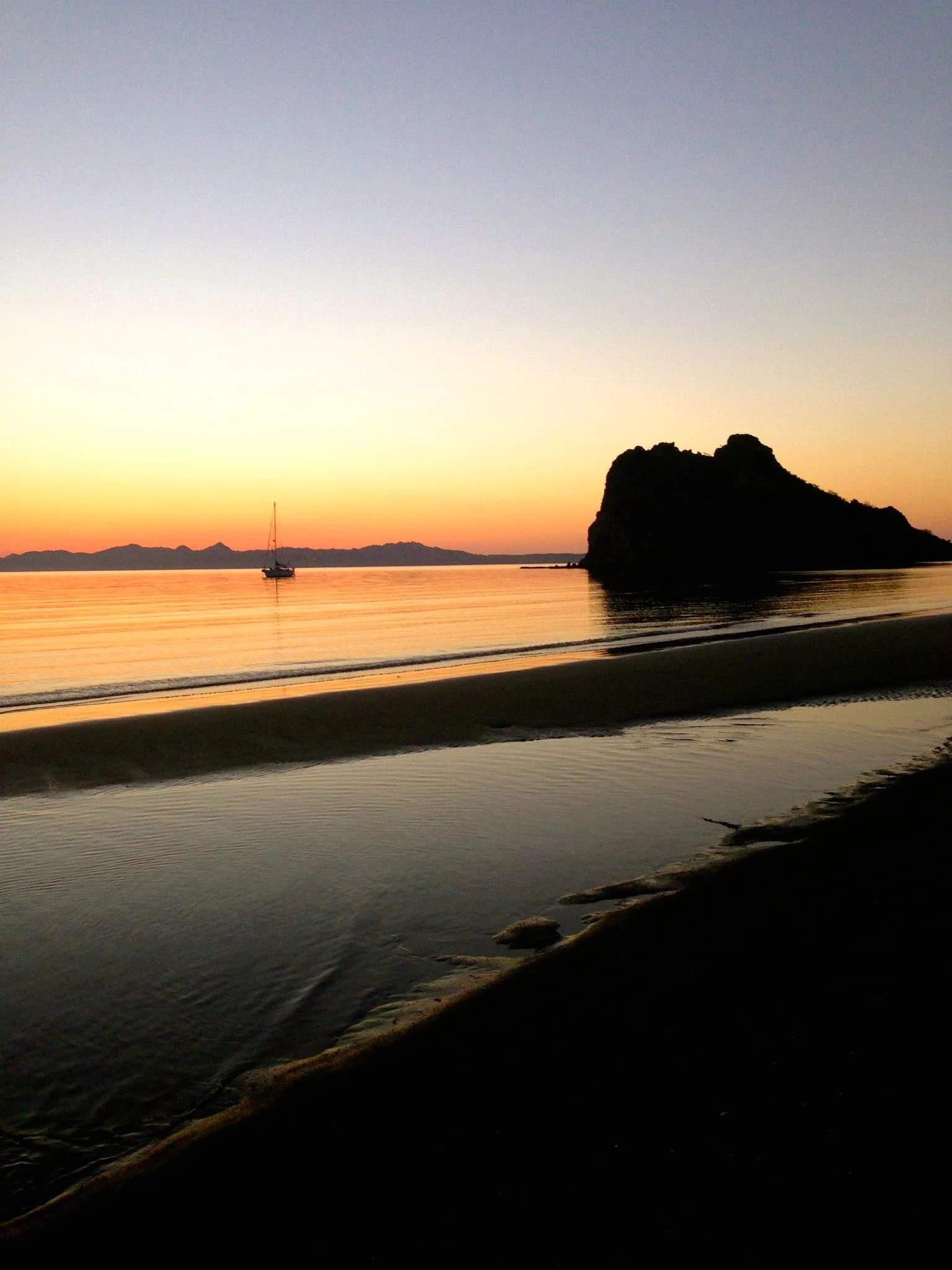 Walking along the beach at sunrise from a Loreto Retreats vacation home; looking at Nopolo Rock, a sailboat, and Carmen Island in the distance. Photo by Rachel Reynolds.