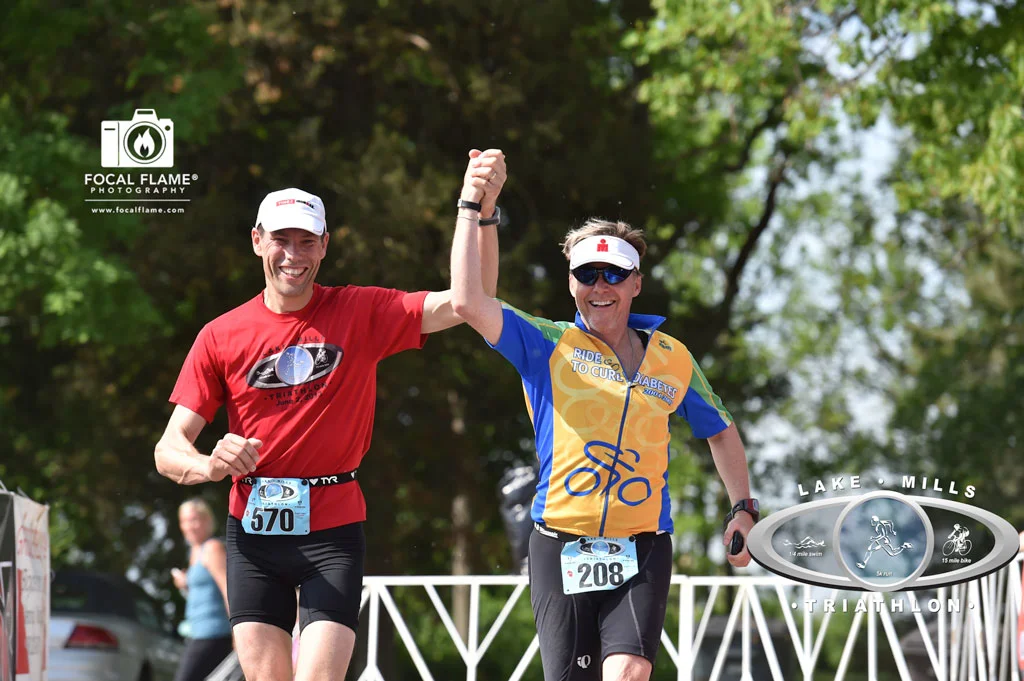 Klaas (left) and Jay (right) cross the finish line of the Lake Mills Triathlon, hand in triumphant hand. (c) 2014 Focal Flame Photography. Photo credit: Clint Thayer